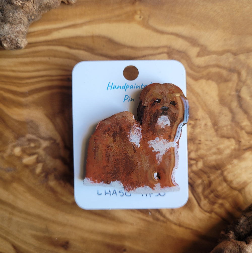 Dog-shaped lhaso apso hand-painted pin displayed on a wooden surface
