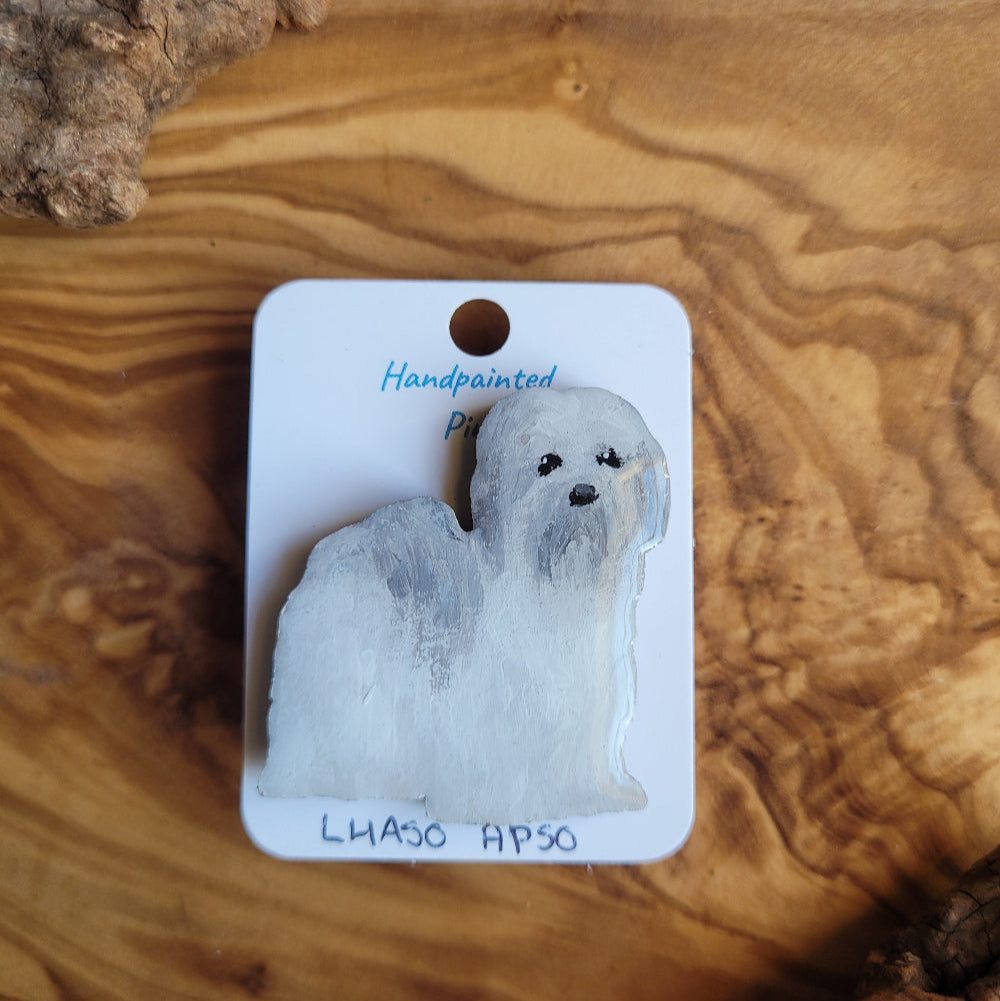Handpainted wooden pin of a Lhasa Apso dog displayed on a wooden surface