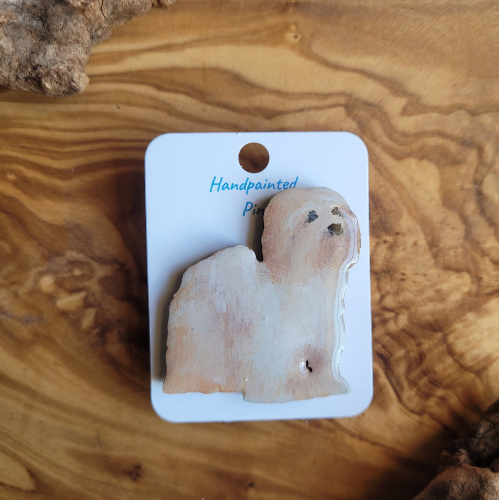 Handpainted Lhaso Apso dog pin displayed on a wooden surface