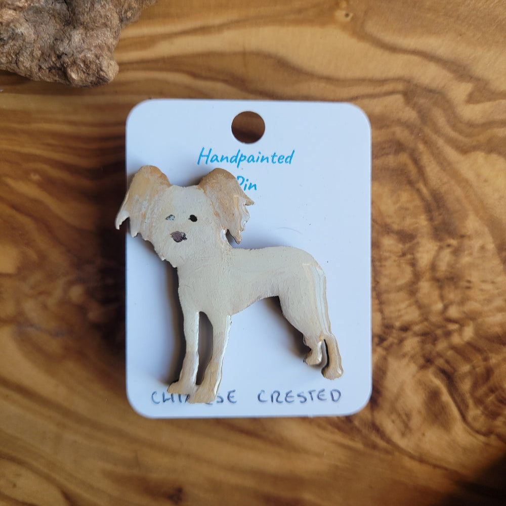 Handpainted chinese crested dog pin on a wooden surface