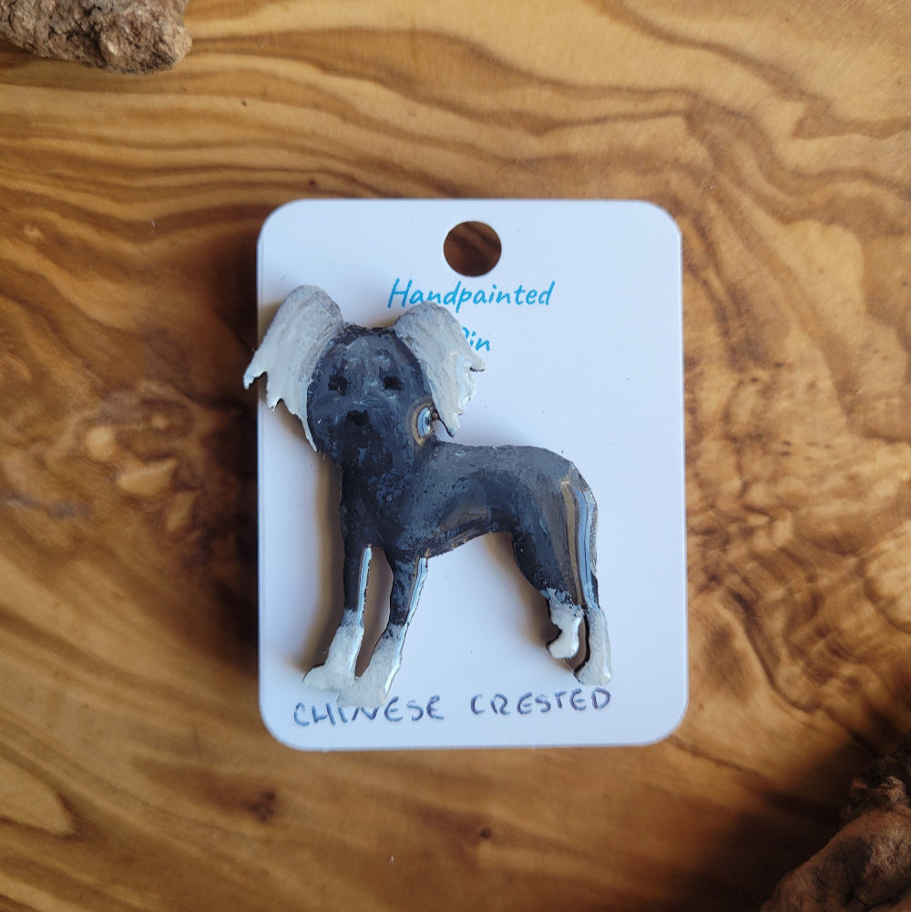 Handpainted chinese crested dog pin on a wooden surface