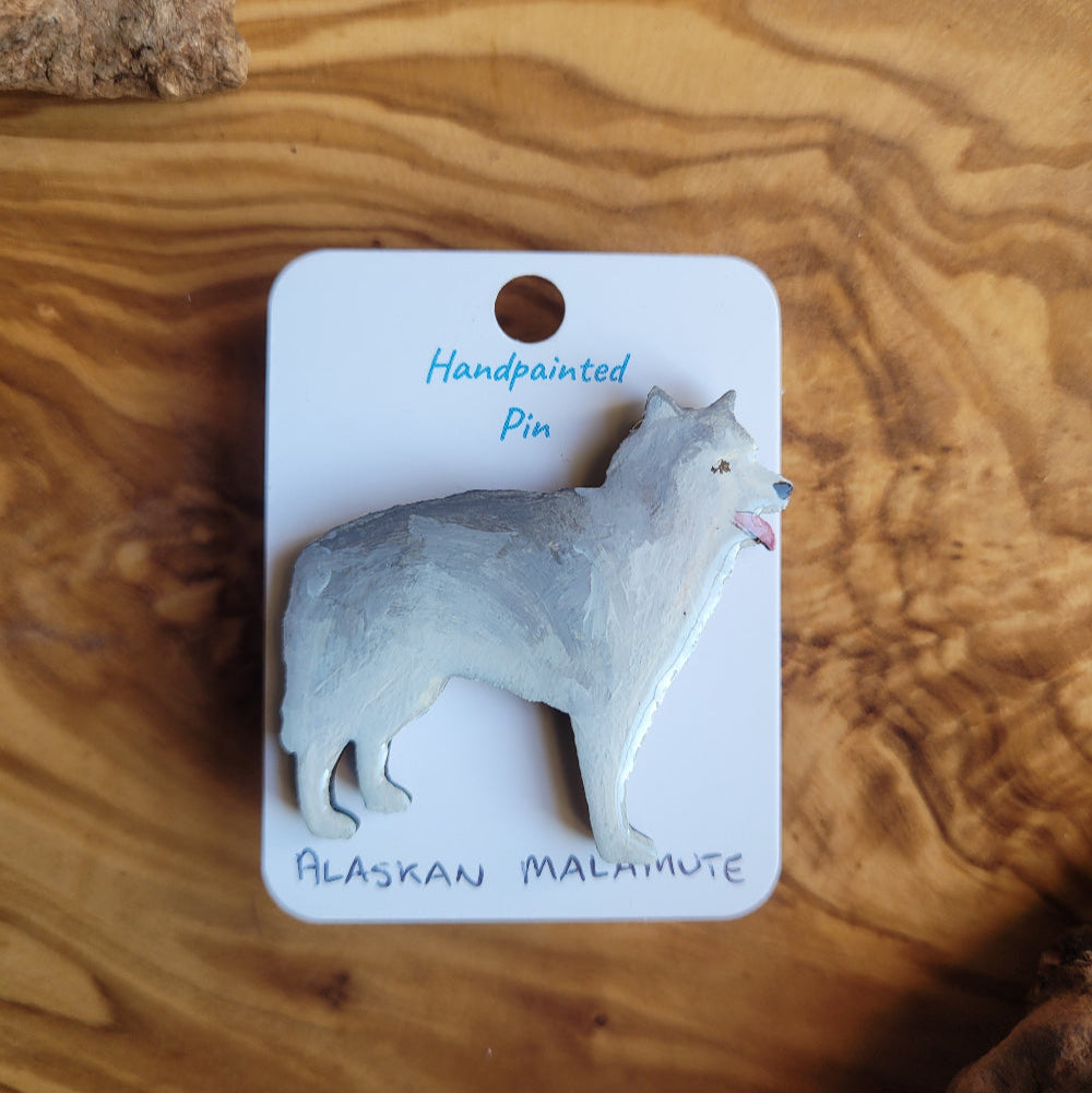 Handpainted Alaskan Malamute dog pin on a wooden surface