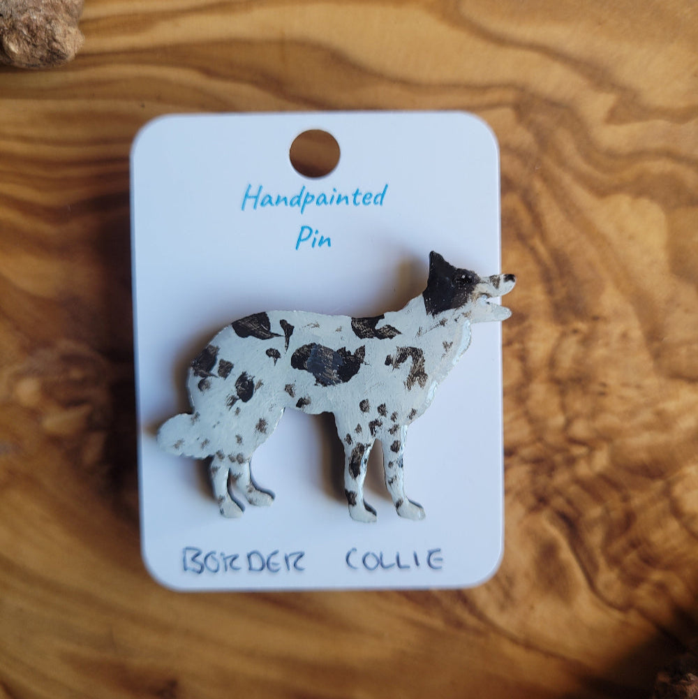 Dog-shaped pin on a white card with text, placed on a wooden surface
