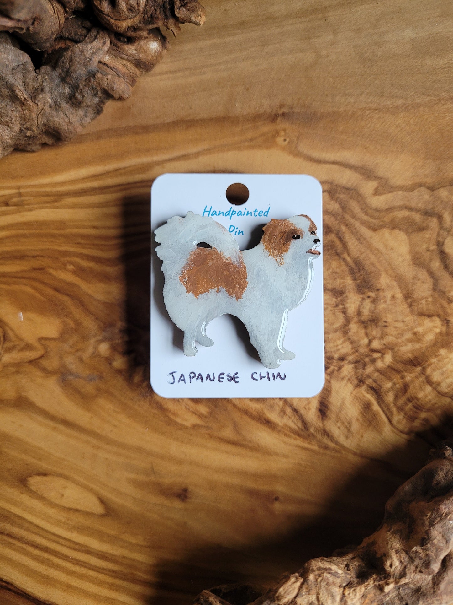 Red and white coloured, hand-painted, wooden pin badge of a Japanese Chin dog