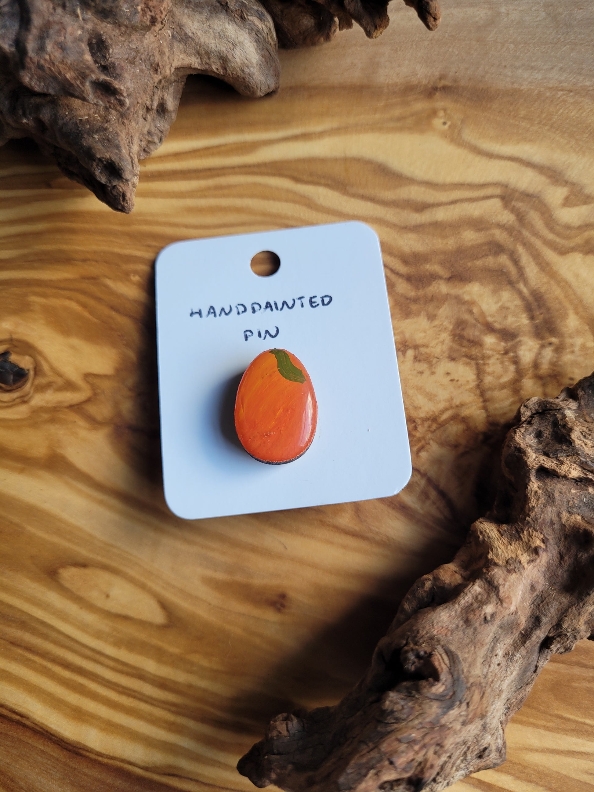 Hand-painted wooden Easter Egg shaped pin badge painted to look like an orange with a little leaf