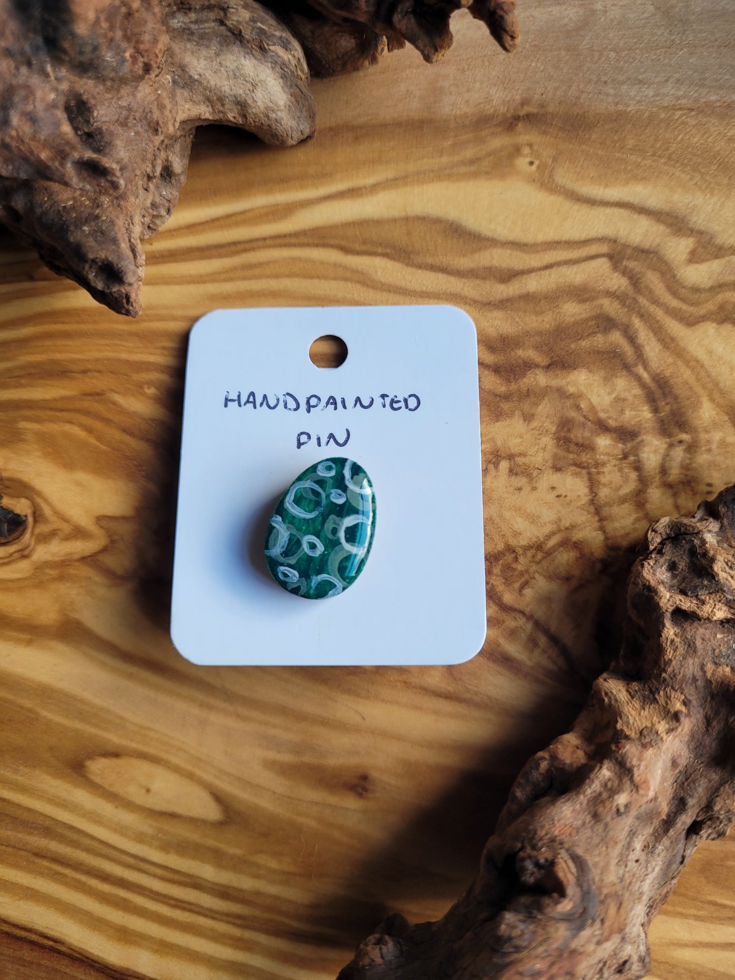Hand-painted wooden Easter Egg shaped pin badge with varying shades of green and silver overlapping circles