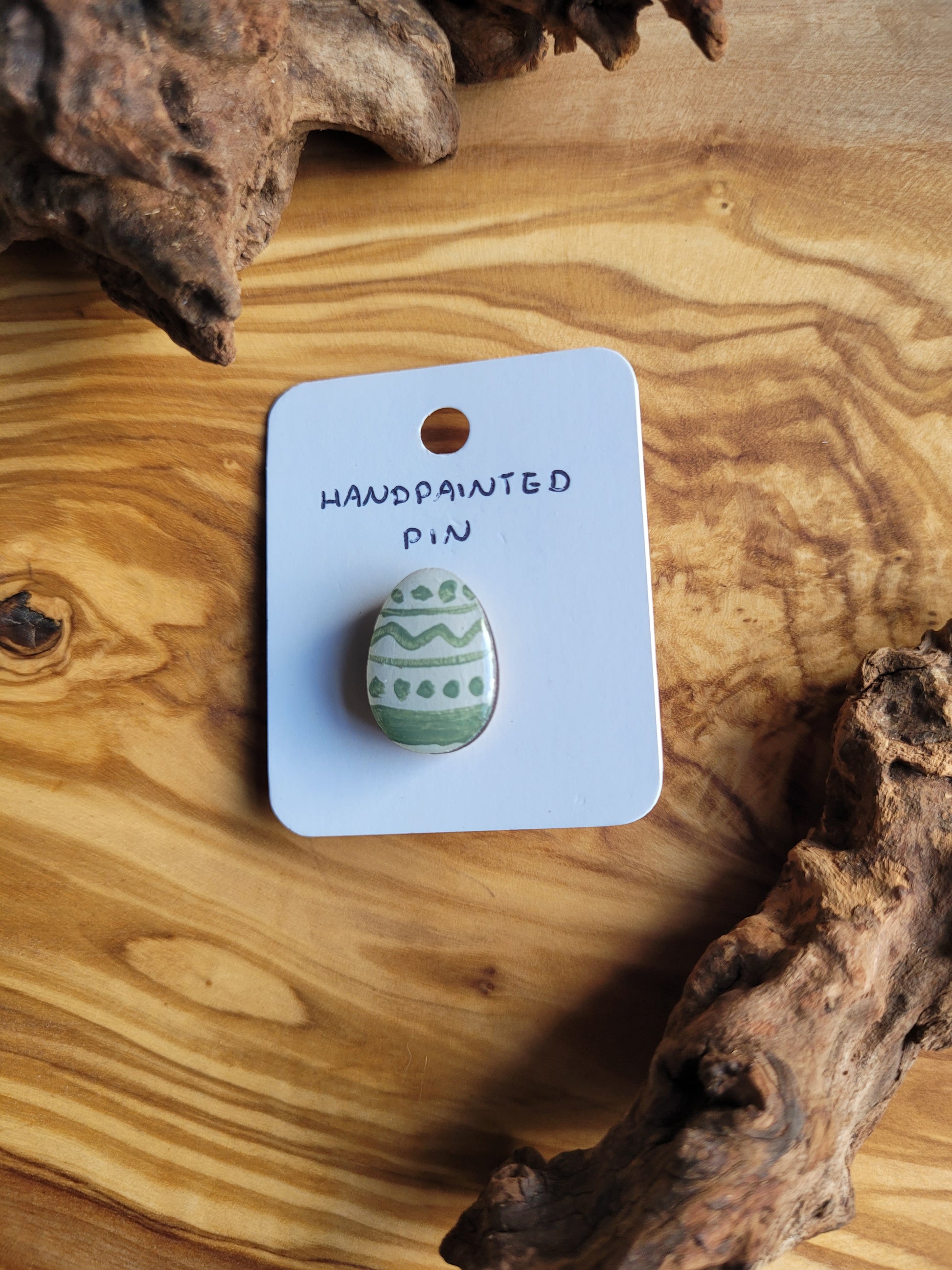 Hand-painted wooden Easter Egg shaped pin badge with sage green lines and dots patterned across a white background