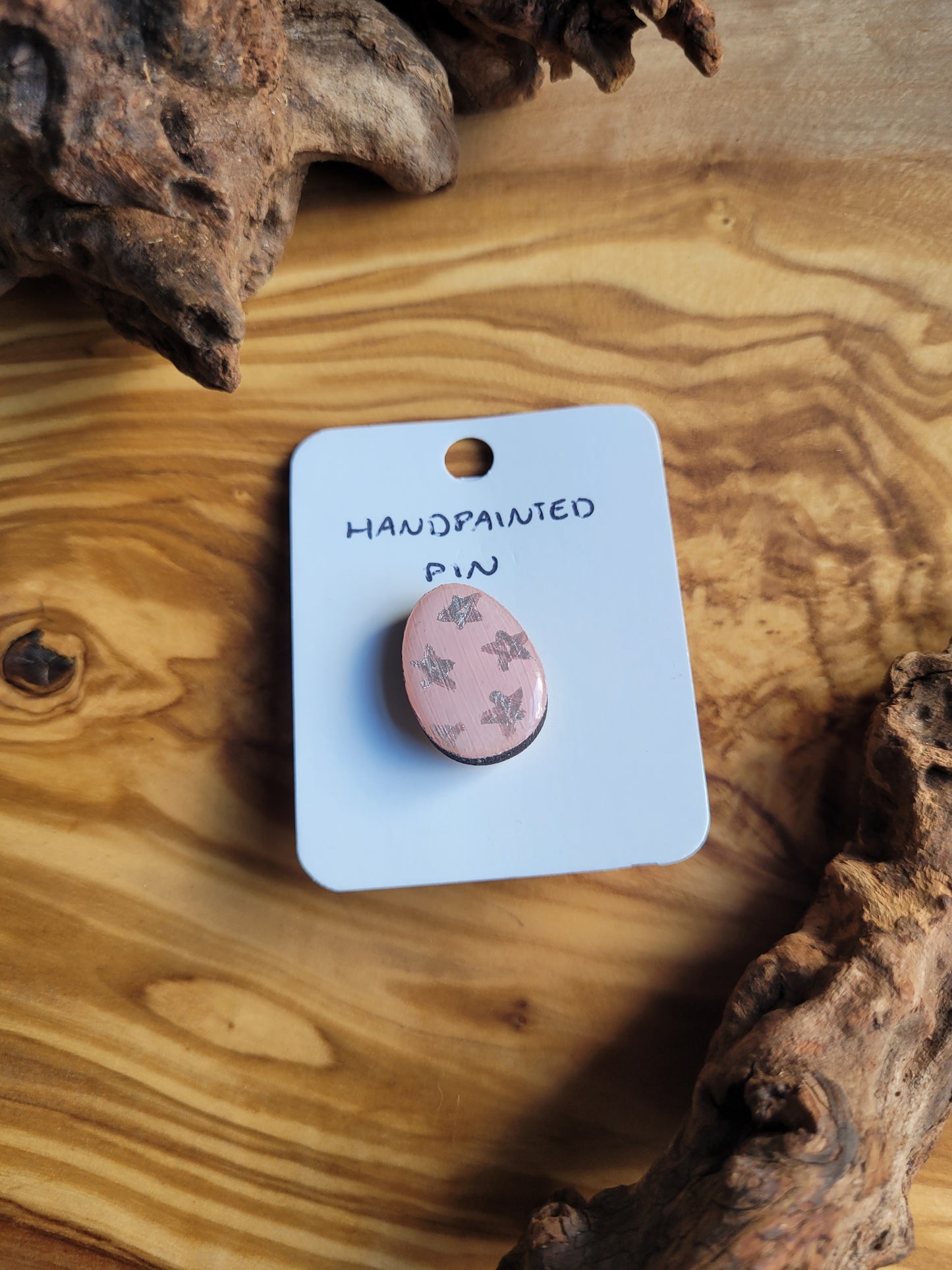 Hand-painted wooden Easter Egg shaped pin badge with silver stars on a pink background 