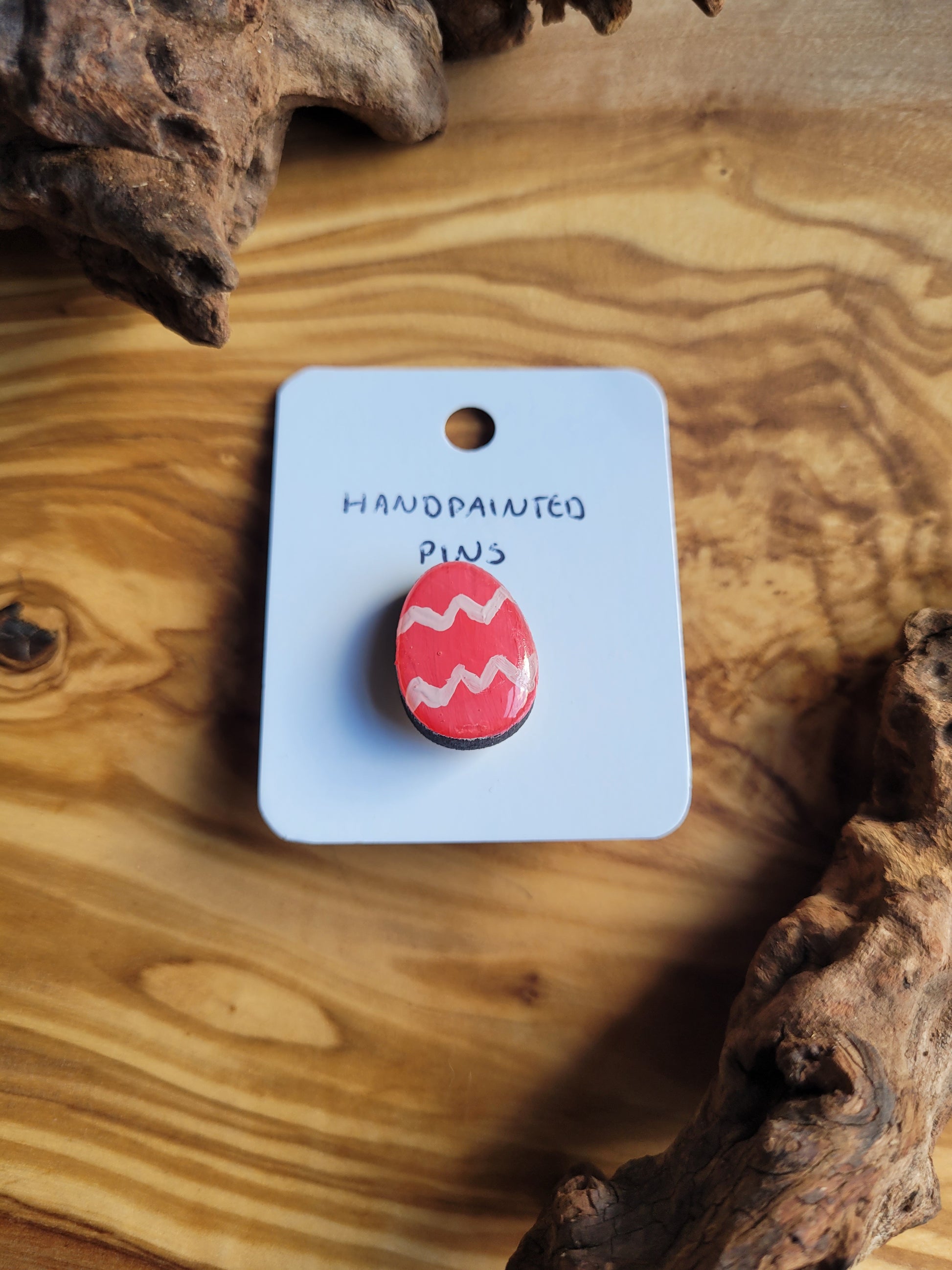 Hand-painted wooden Easter Egg shaped pin badge with two liht pink zigzags across a pink background
