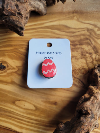 Hand-painted wooden Easter Egg shaped pin badge with two liht pink zigzags across a pink background