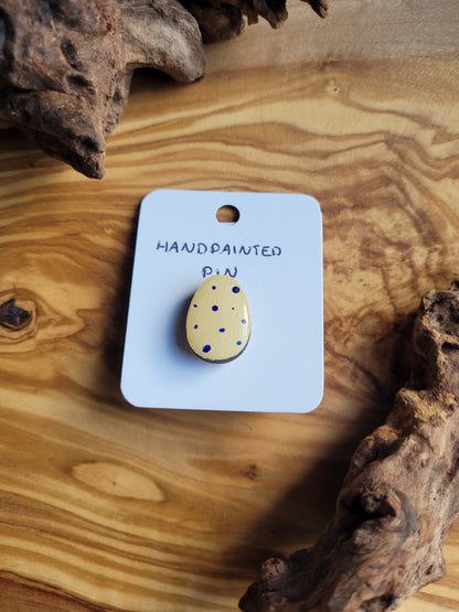 Hand-painted wooden Easter Egg shaped pin badge with blue dots on a yellow background