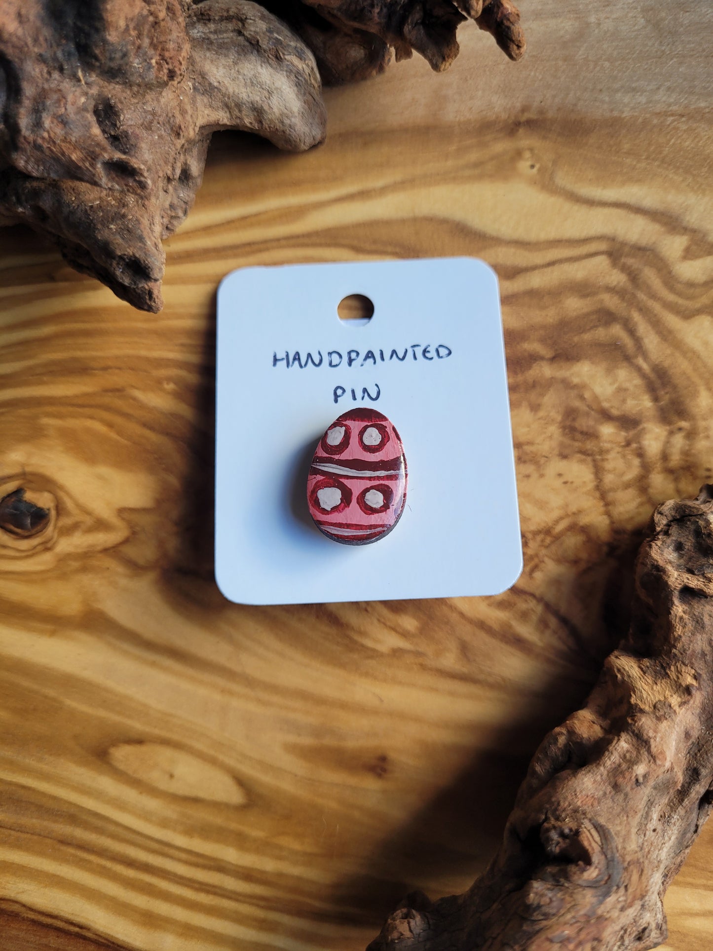 Hand-painted wooden Easter Egg shaped pin badge with varying shades of pink and white patterned circles and lines