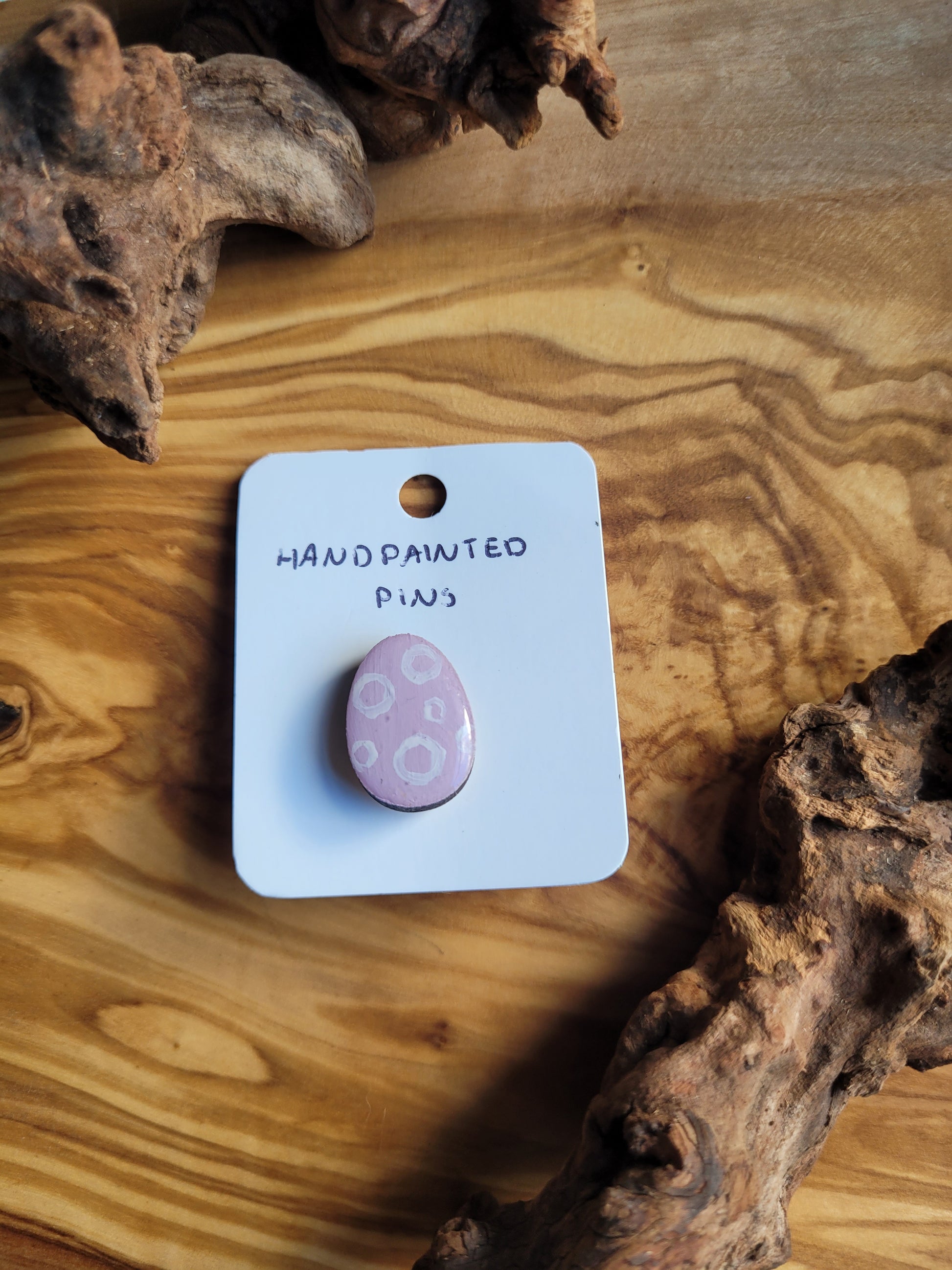 Hand-painted wooden Easter Egg shaped pin badge with white circles on a pink background