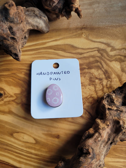 Hand-painted wooden Easter Egg shaped pin badge with white circles on a pink background