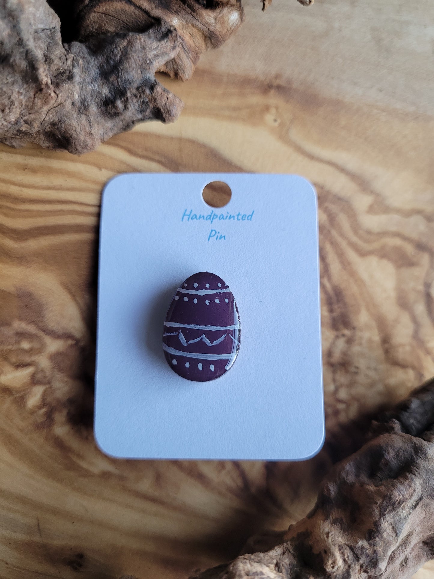 Hand-painted wooden Easter Egg shaped pin badge with white patterned lines, dots and zigzags across a deep purple background