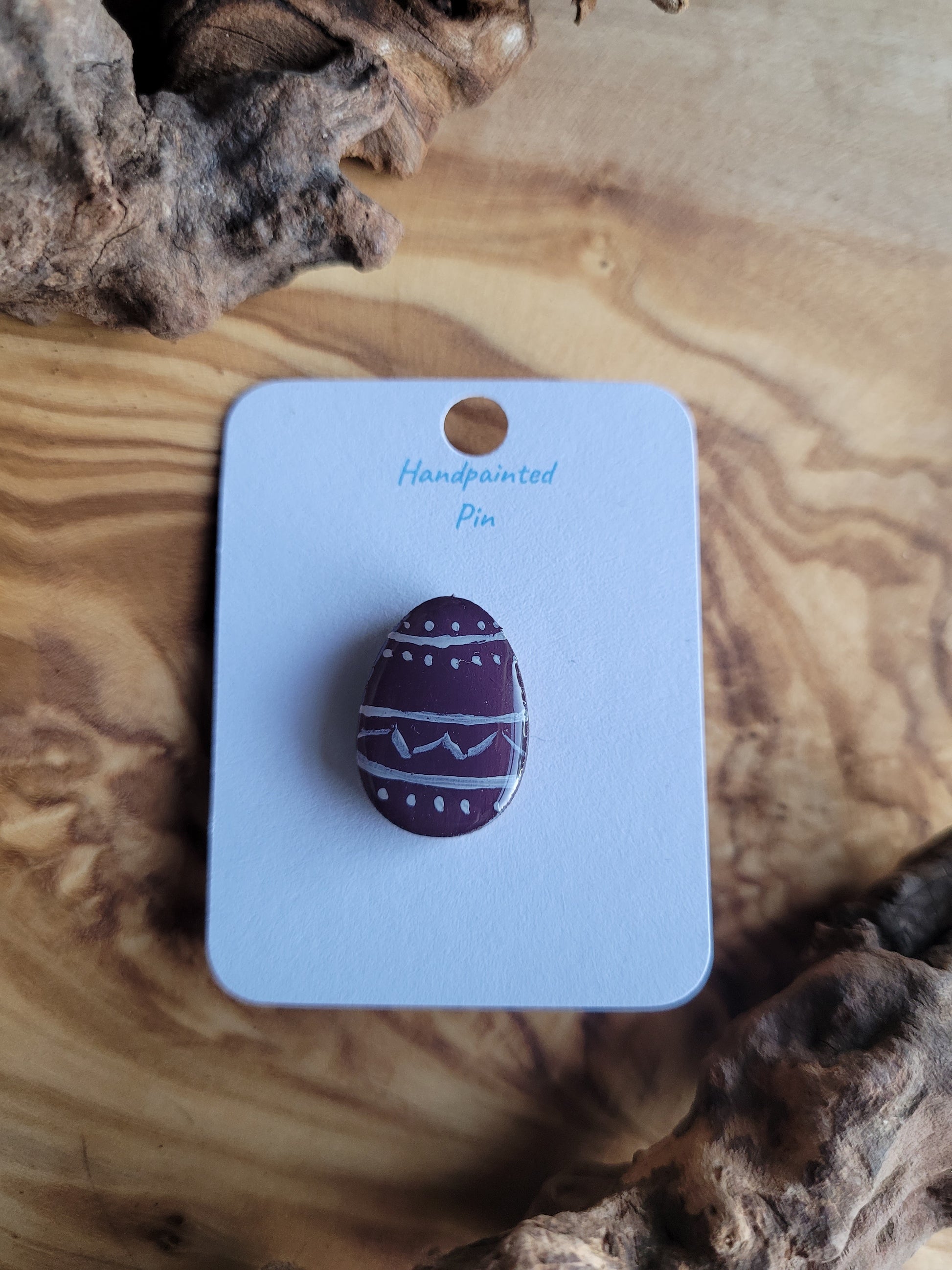 Hand-painted wooden Easter Egg shaped pin badge with white patterned lines, dots and zigzags across a deep purple background