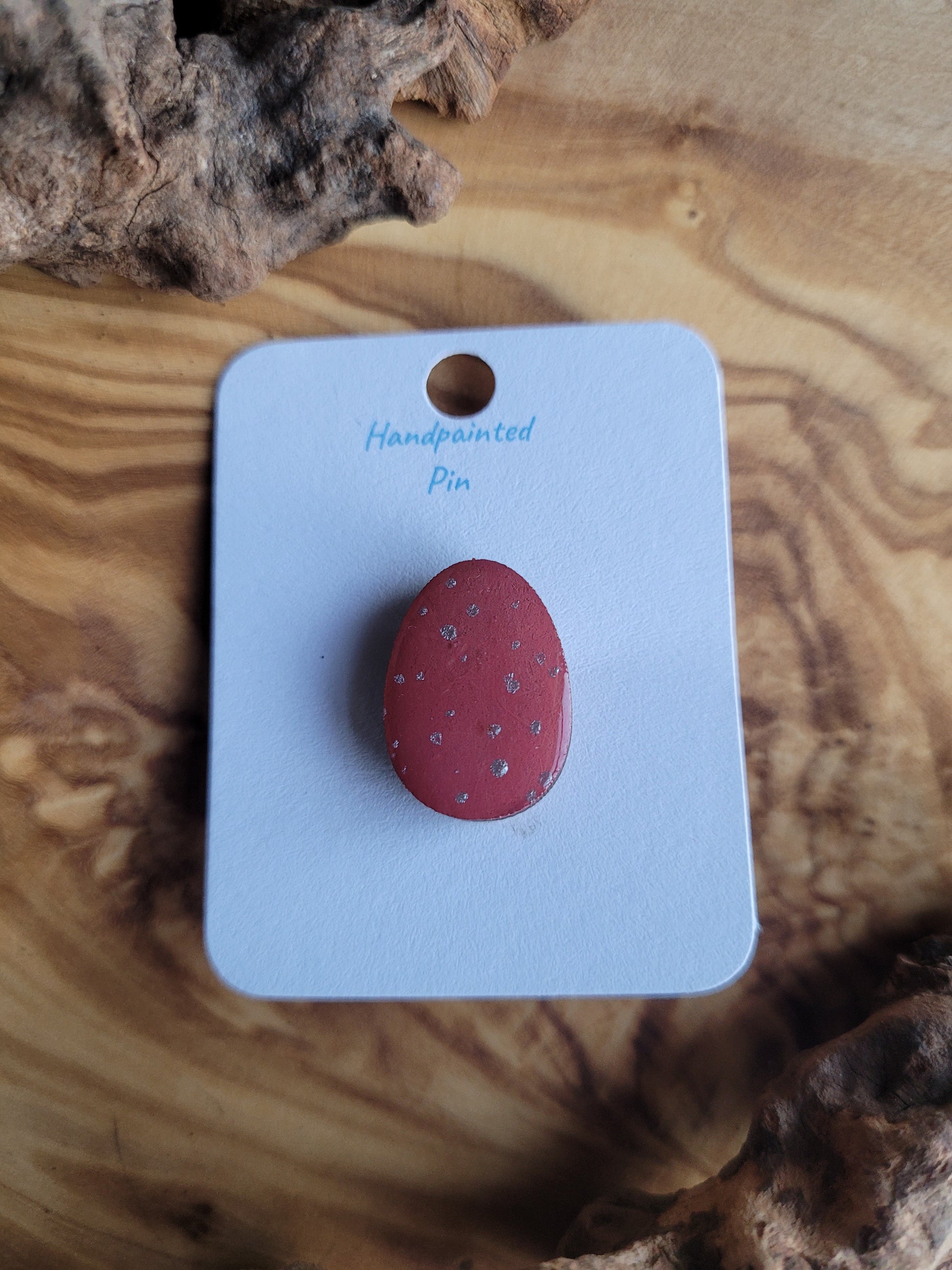 Hand-painted wooden Easter Egg shaped pin badge with silver dots on a deep coral pink background