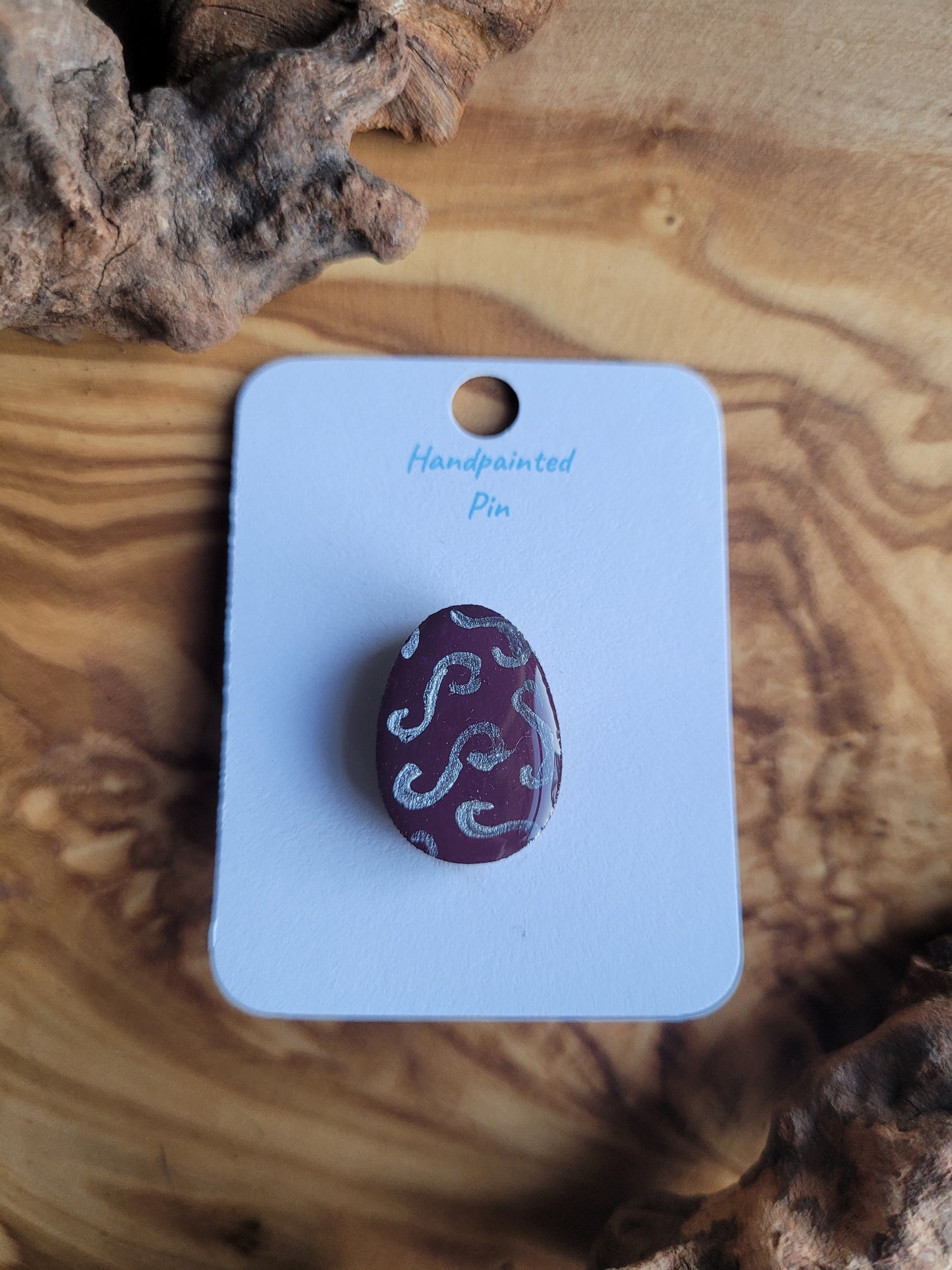 Hand-painted wooden Easter Egg shaped pin badge with silver swirls on a purple background