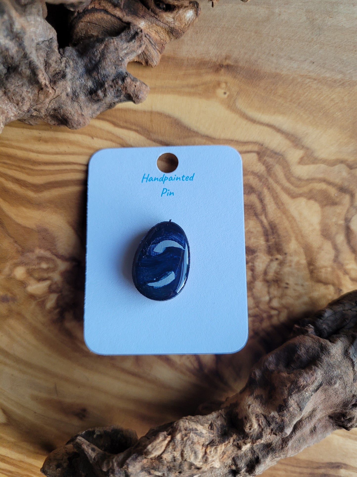 Hand-painted wooden Easter Egg shaped pin badge with silver swirls on a navy background