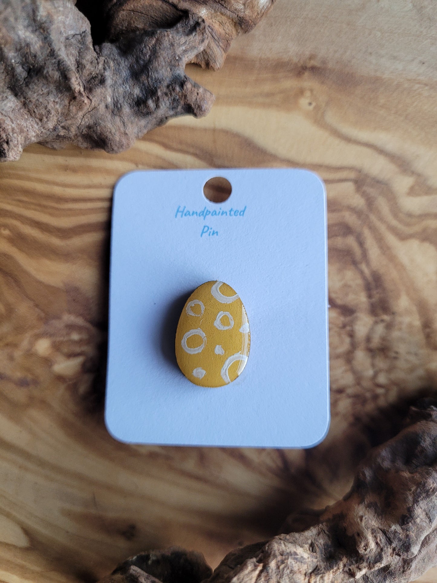 Hand-painted wooden Easter Egg shaped pin badge with white circles over a yellow background