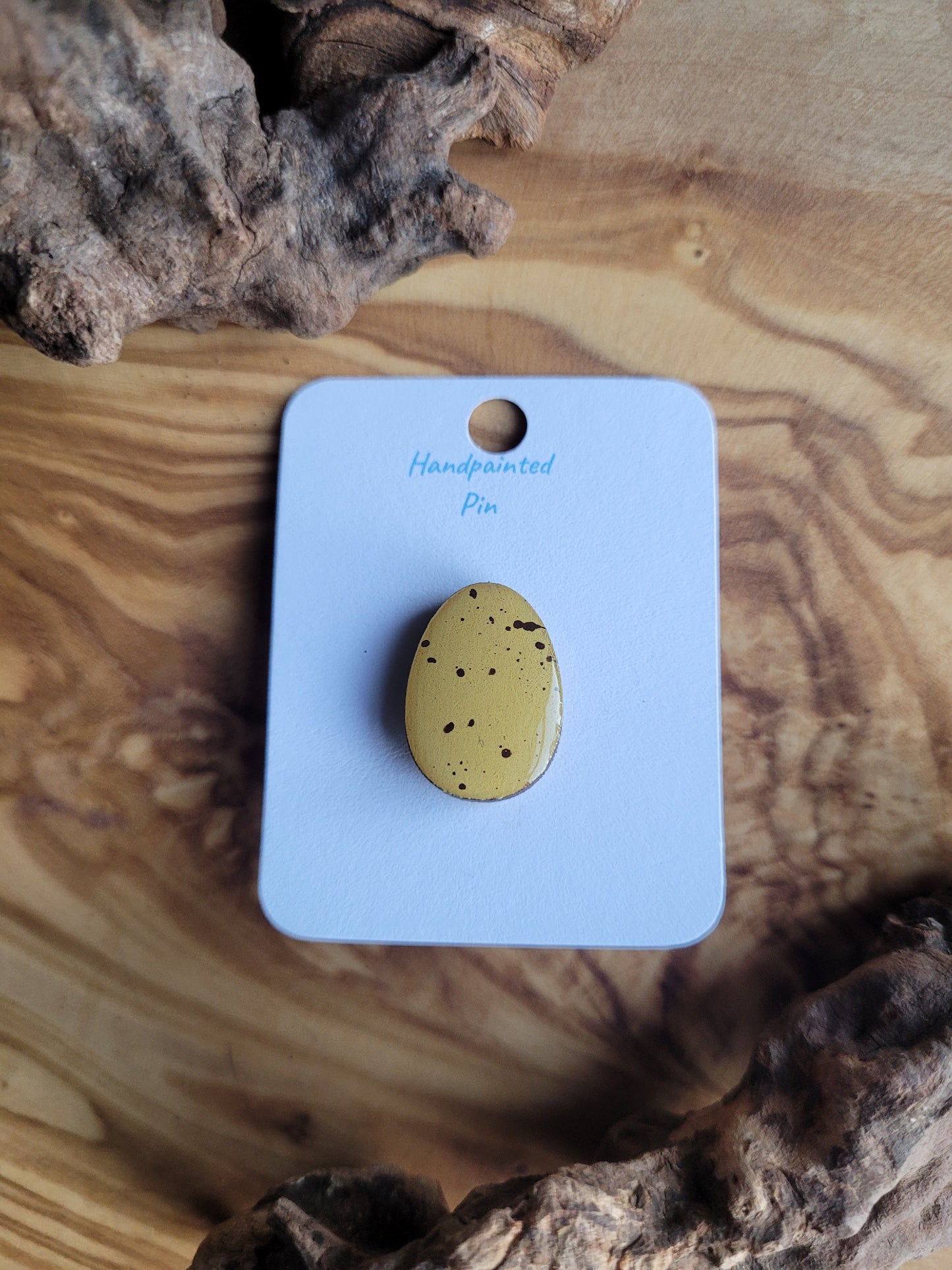 Hand-painted wooden Easter Egg shaped pin badge with dark speckles on yellow like a mini egg
