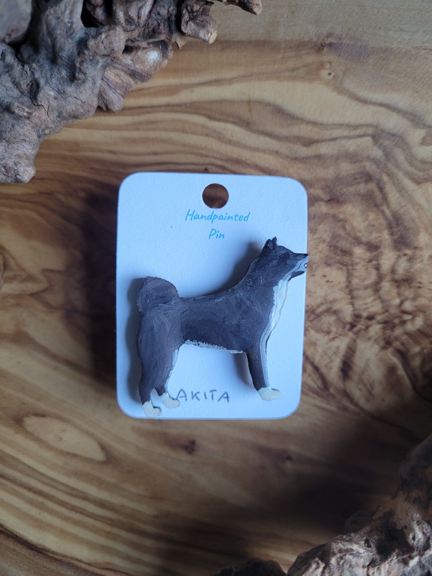 hand-painted wooden pin badge of a black Akita dog