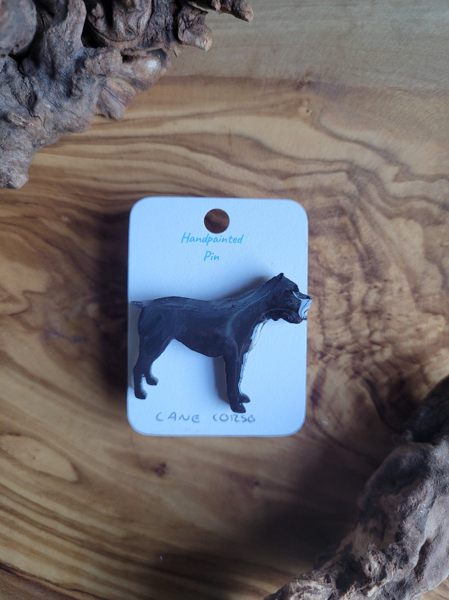 Hand-painted wooden pin badge of a black with a white chest coloured Cane Corso dog.