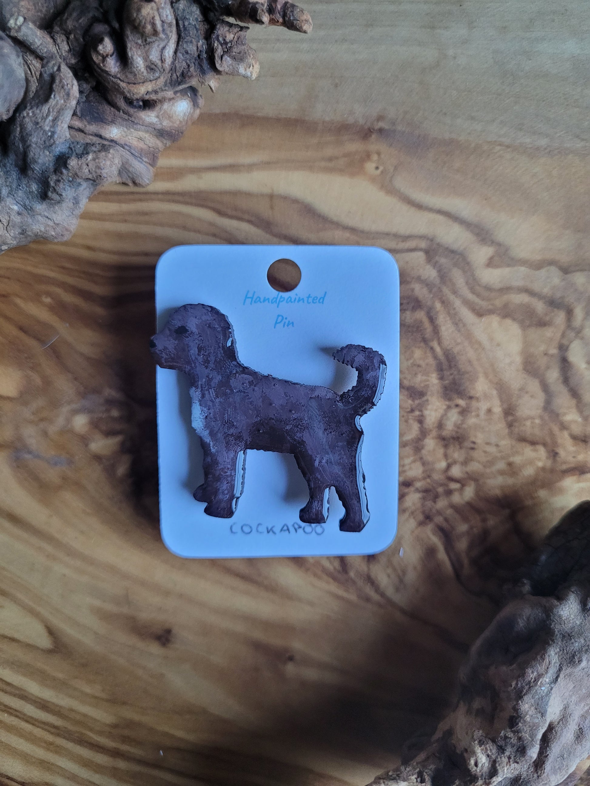 Hand-painted wooden dog pin badge of a chocolate with a white chest coloured Cockapoo