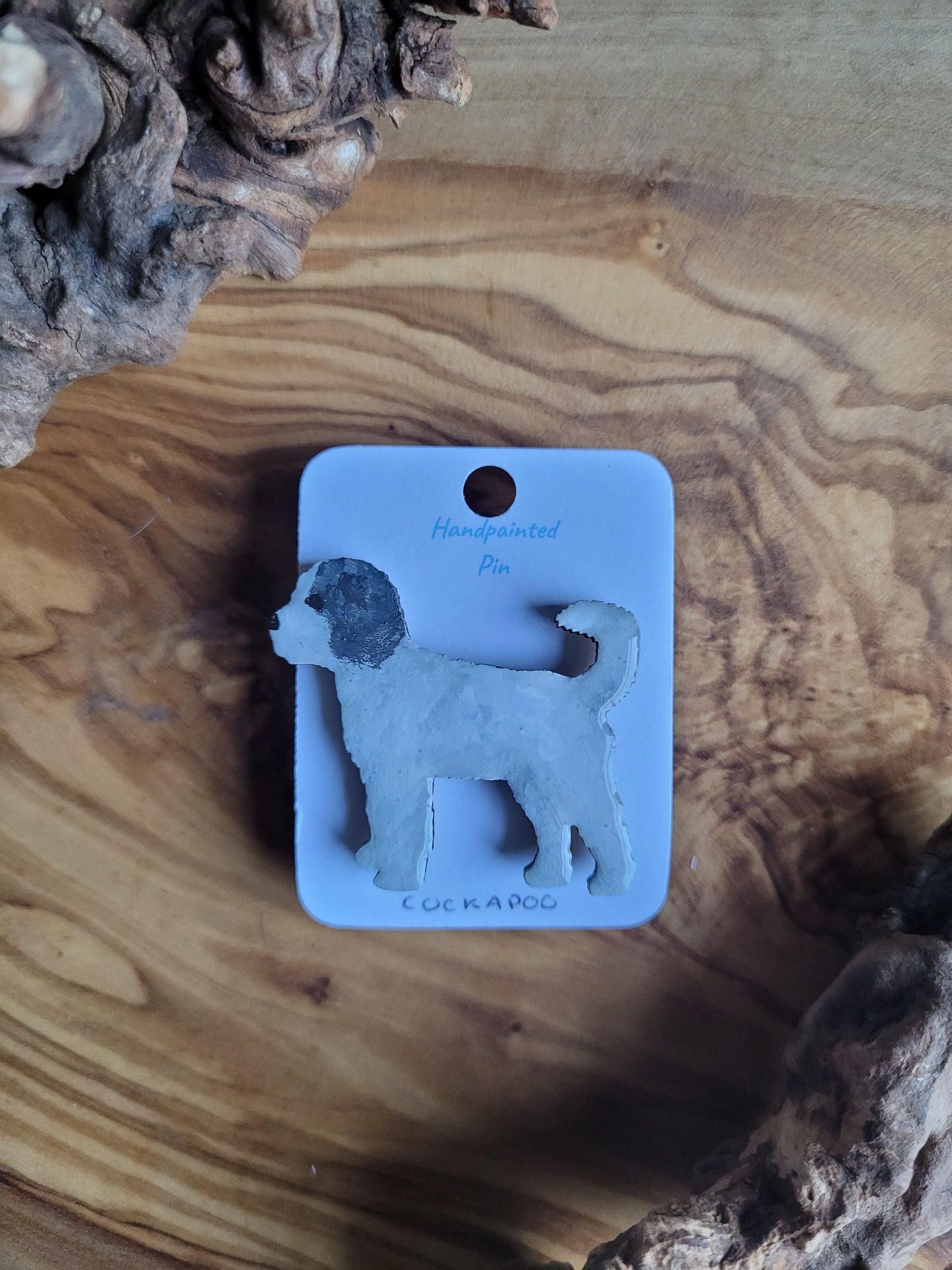 Hand-painted wooden dog pin badge of a white with black ear patches coloured Cockapoo