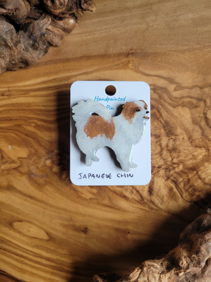 Red and white coloured, hand-painted, wooden pin badge of a Japanese Chin dog
