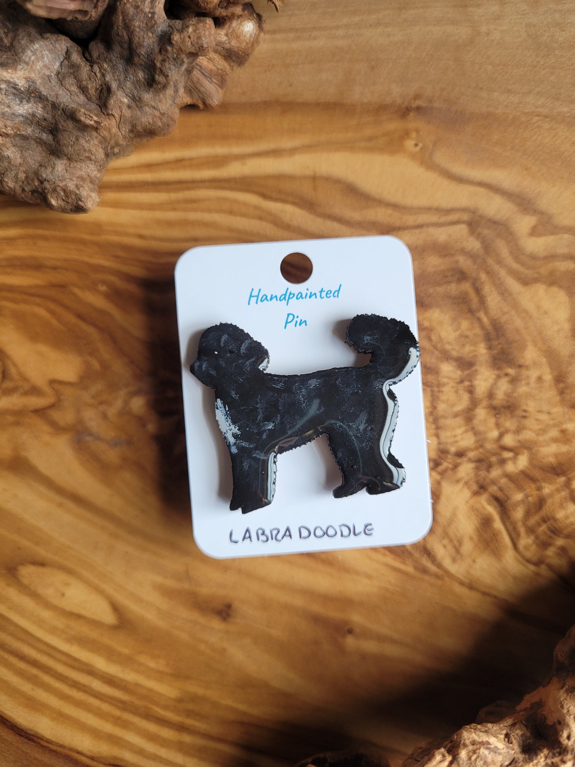 Hand-painted Labdradoodle dog pin badge, painted onto wood and black coloured with a patch of white on the chest