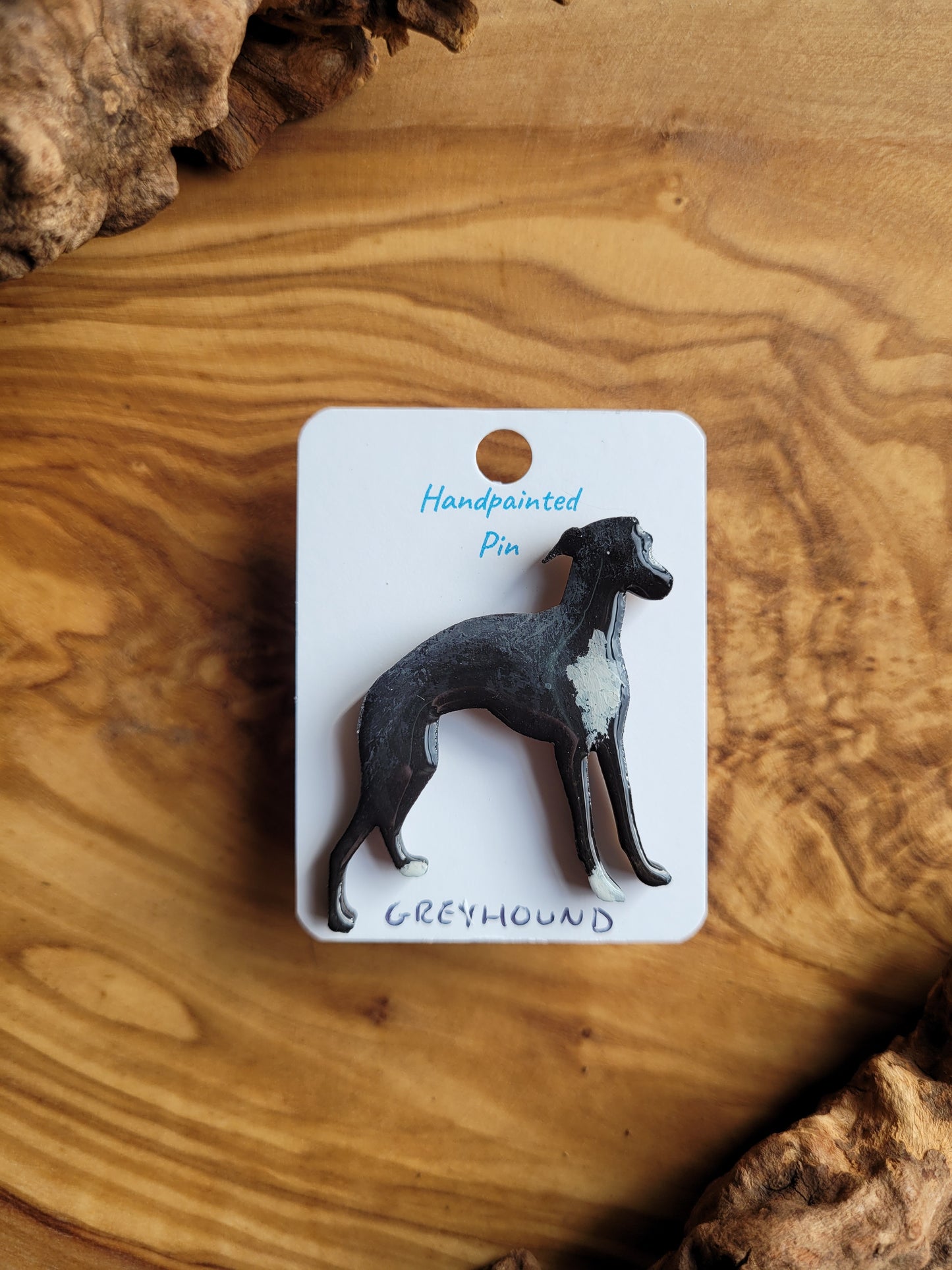 Hand-painted Greyhound pin badge, painted onto wood. Black with white chest and paws