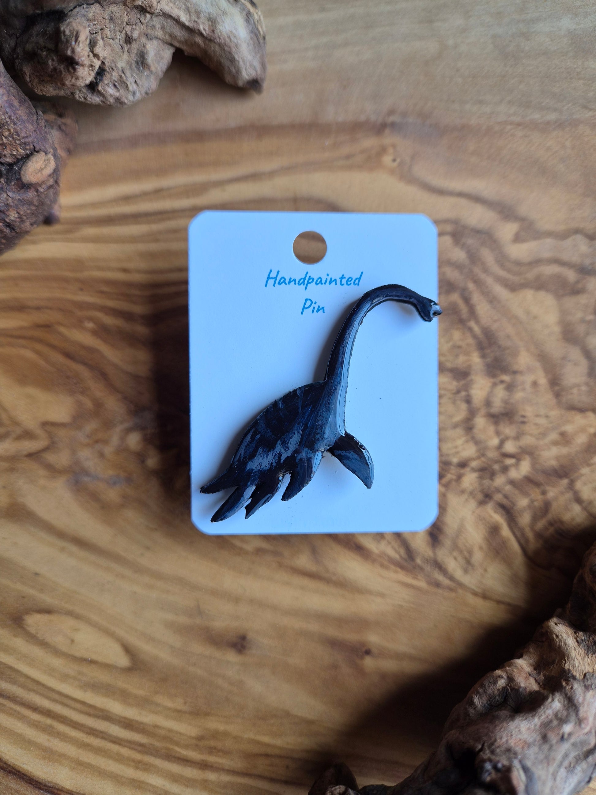 A hand-painted wooden dinosaur pin badge of the plesiosaur dinosaur