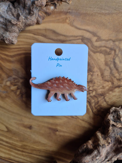 A hand-painted wooden dinosaur pin badge of the Euoplocephalus dinosaur