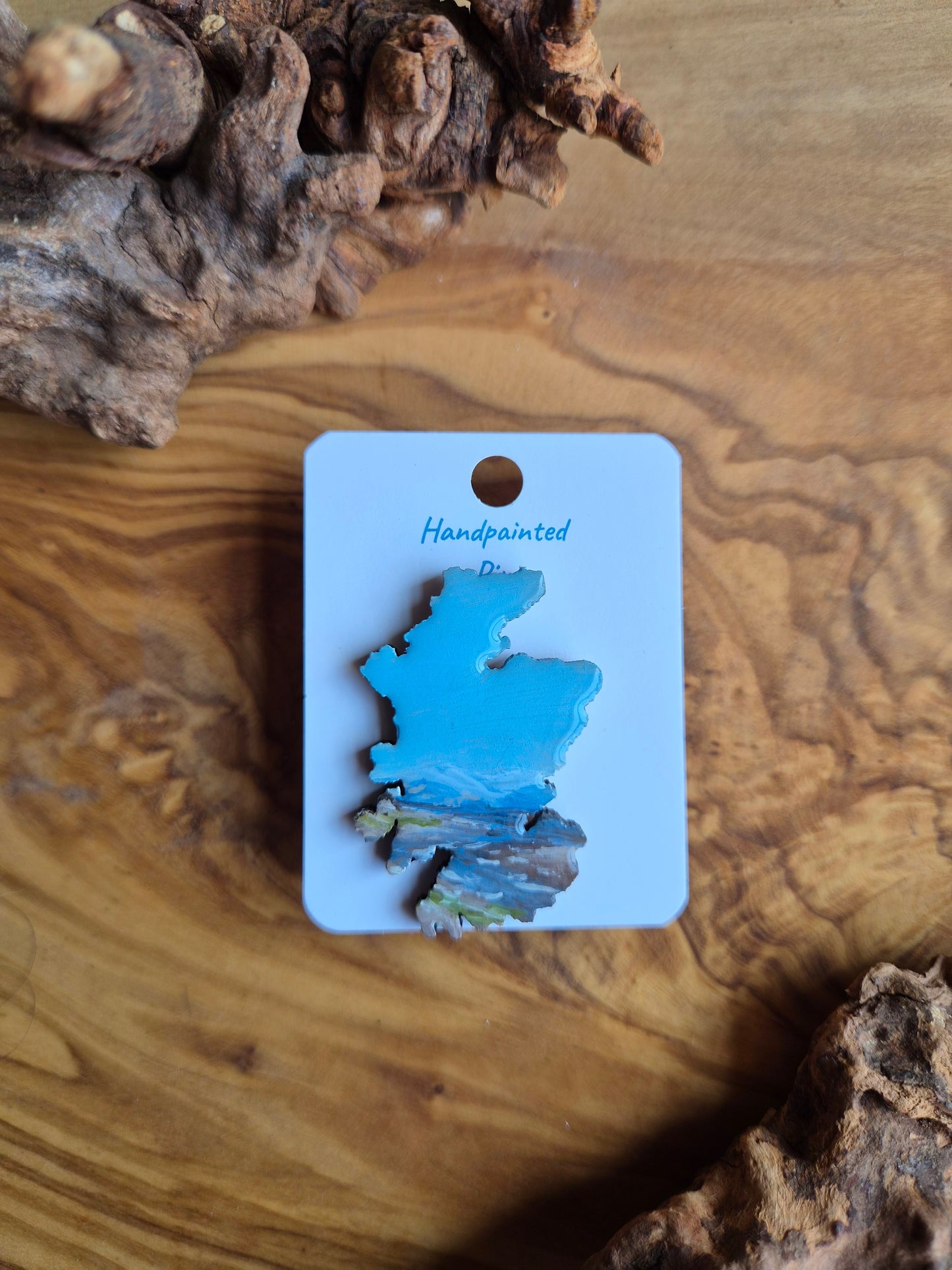 Hand-painted Scotland shaped wooden pin badge with a scottish landscape of findhorn beach painted on