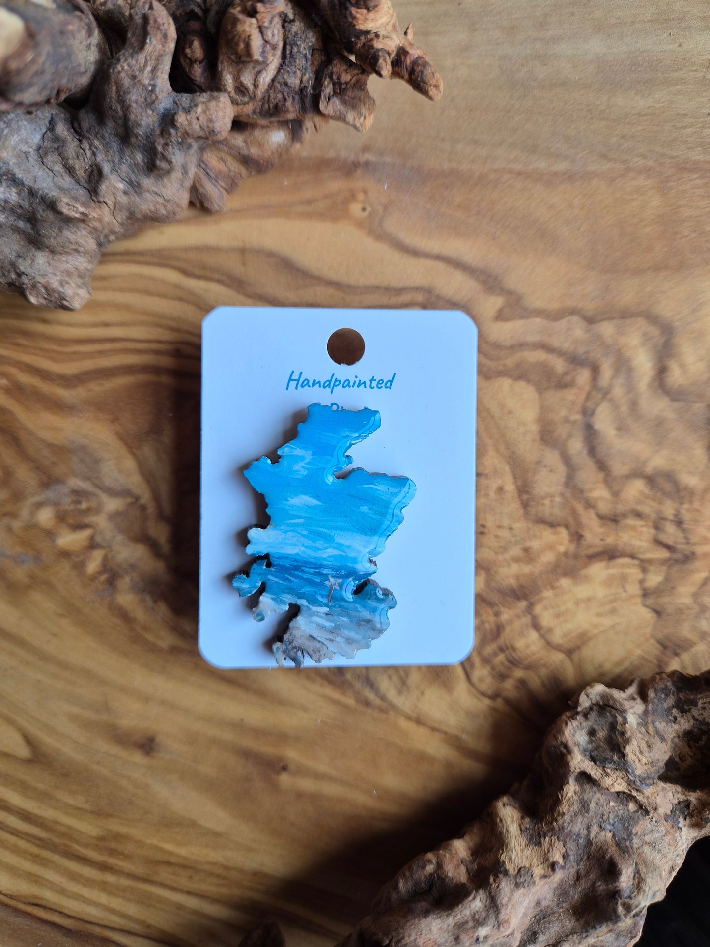 Hand-painted Scotland shaped wooden pin badge with a scottish landscape of findhorn beach painted on