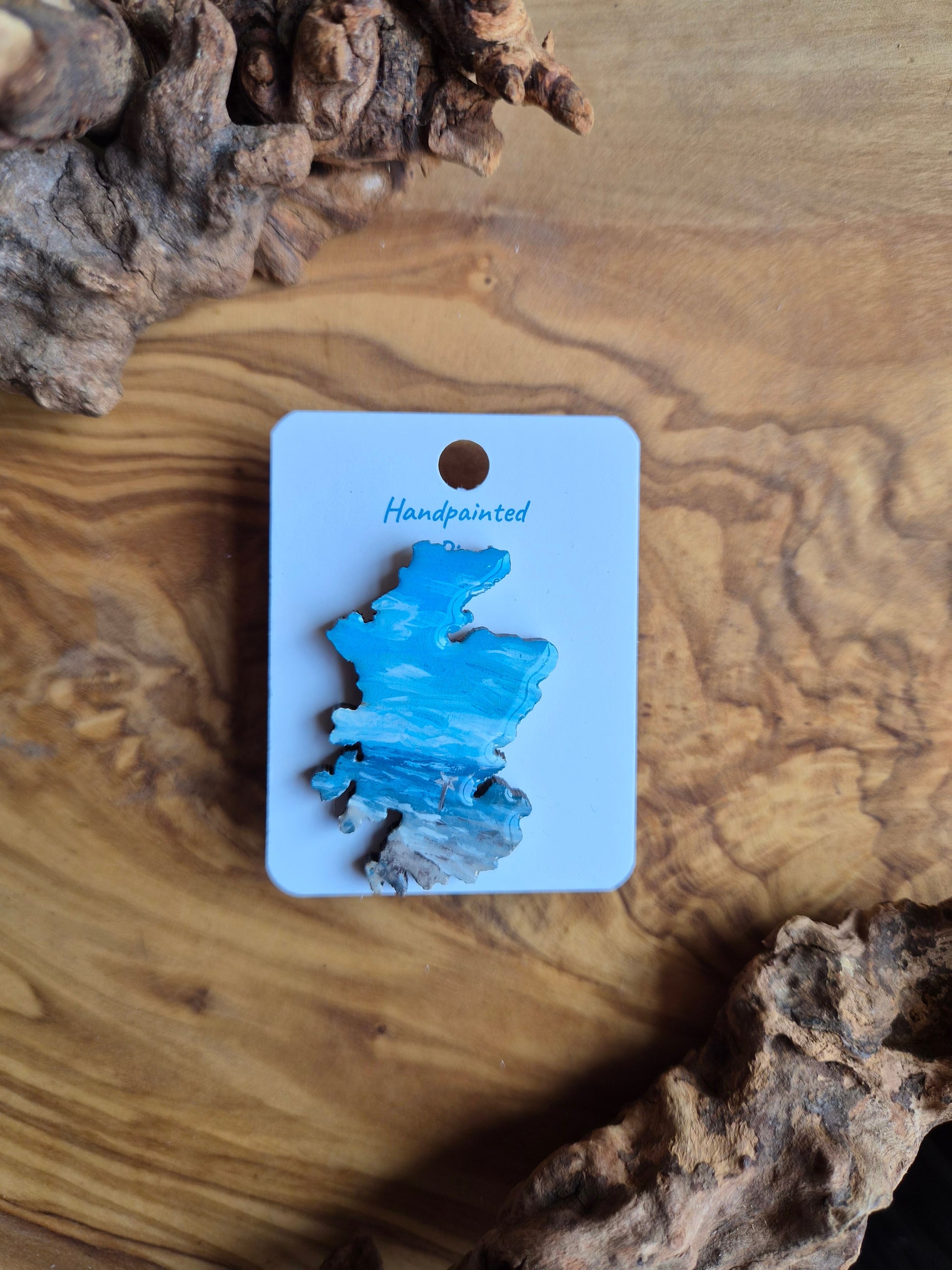 Hand-painted Scotland shaped wooden pin badge with a scottish landscape of findhorn beach painted on