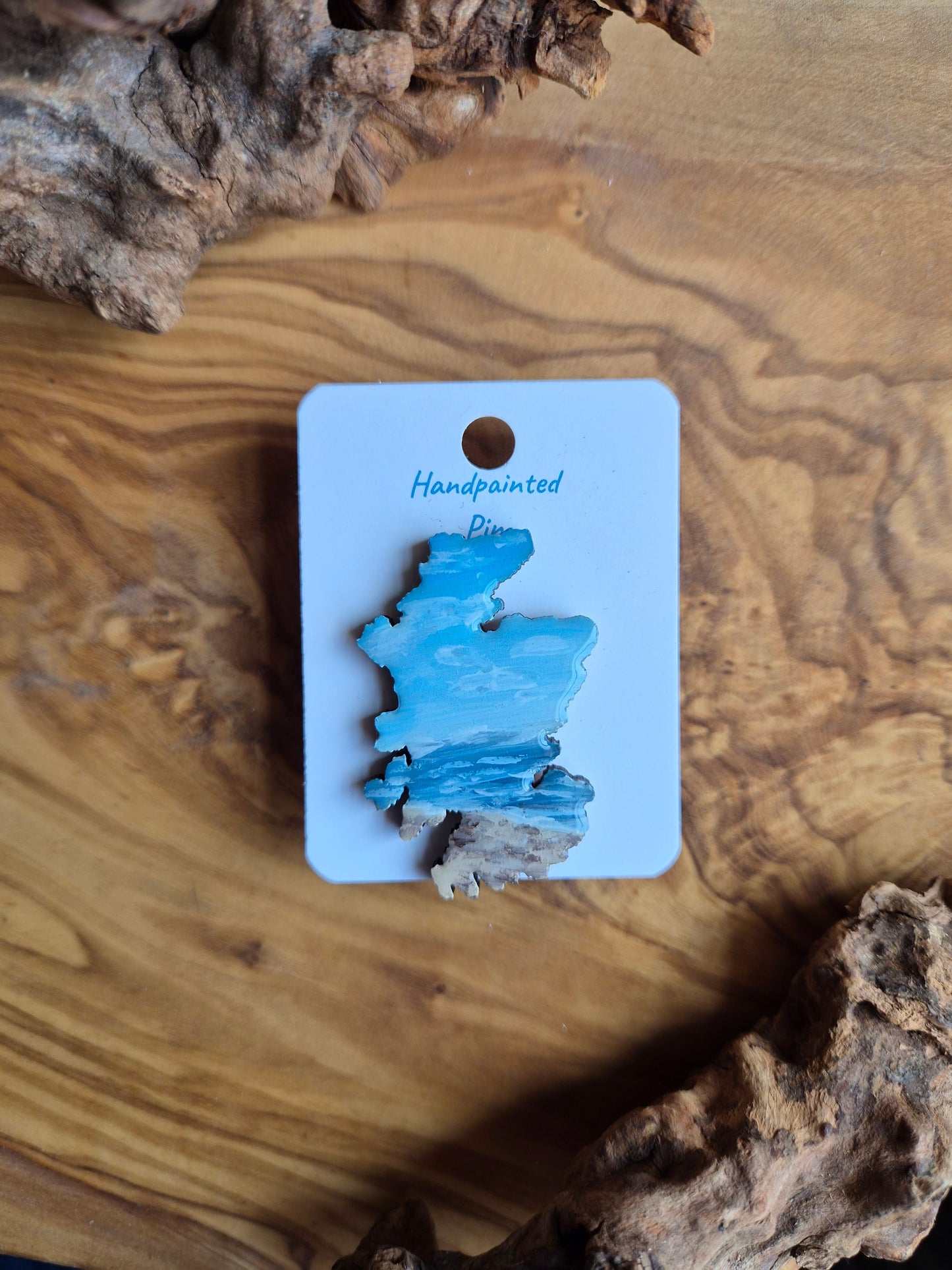 Hand-painted Scotland shaped wooden pin badge with a scottish landscape of findhorn beach painted on