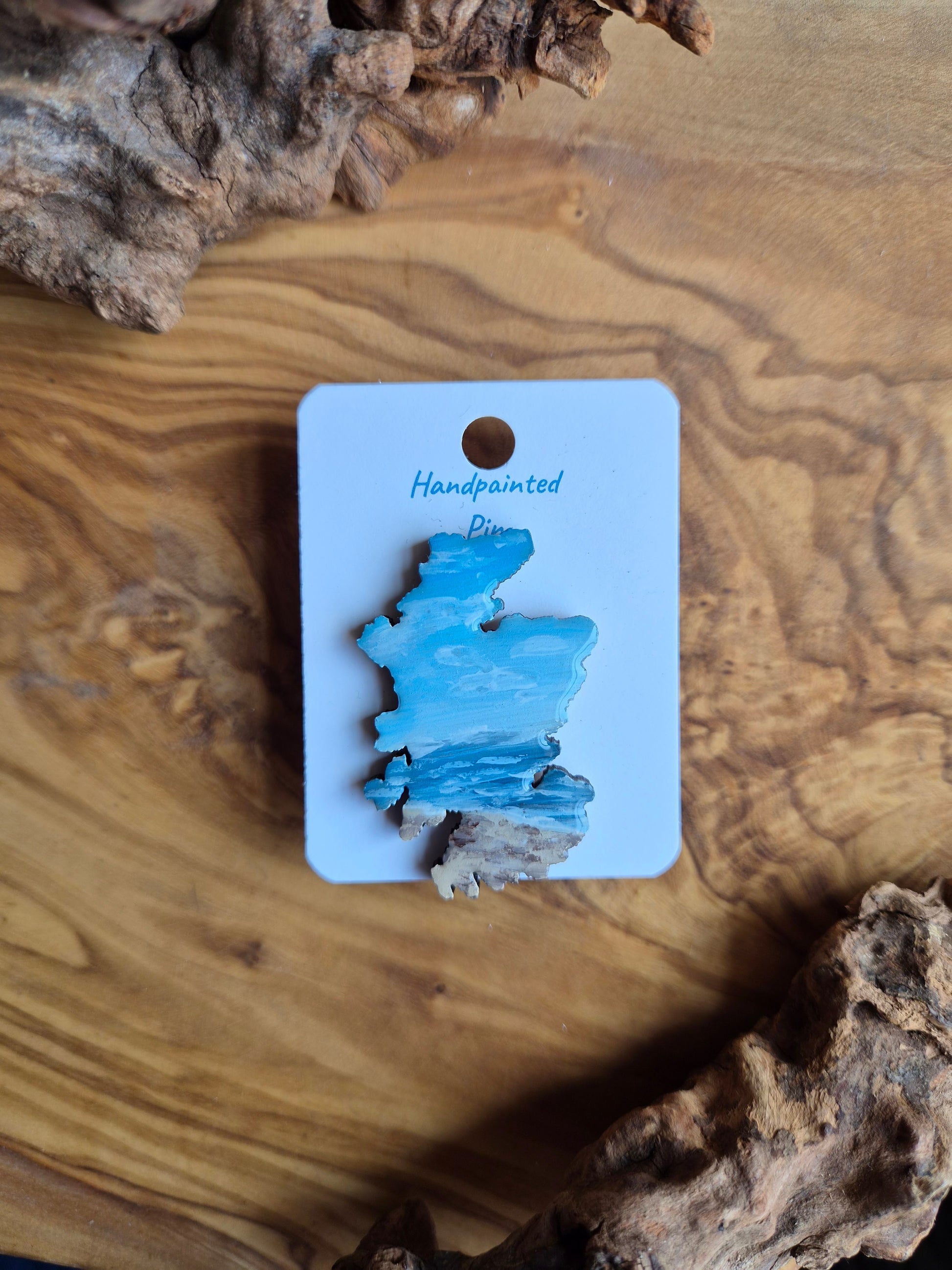 Hand-painted Scotland shaped wooden pin badge with a scottish landscape of findhorn beach painted on