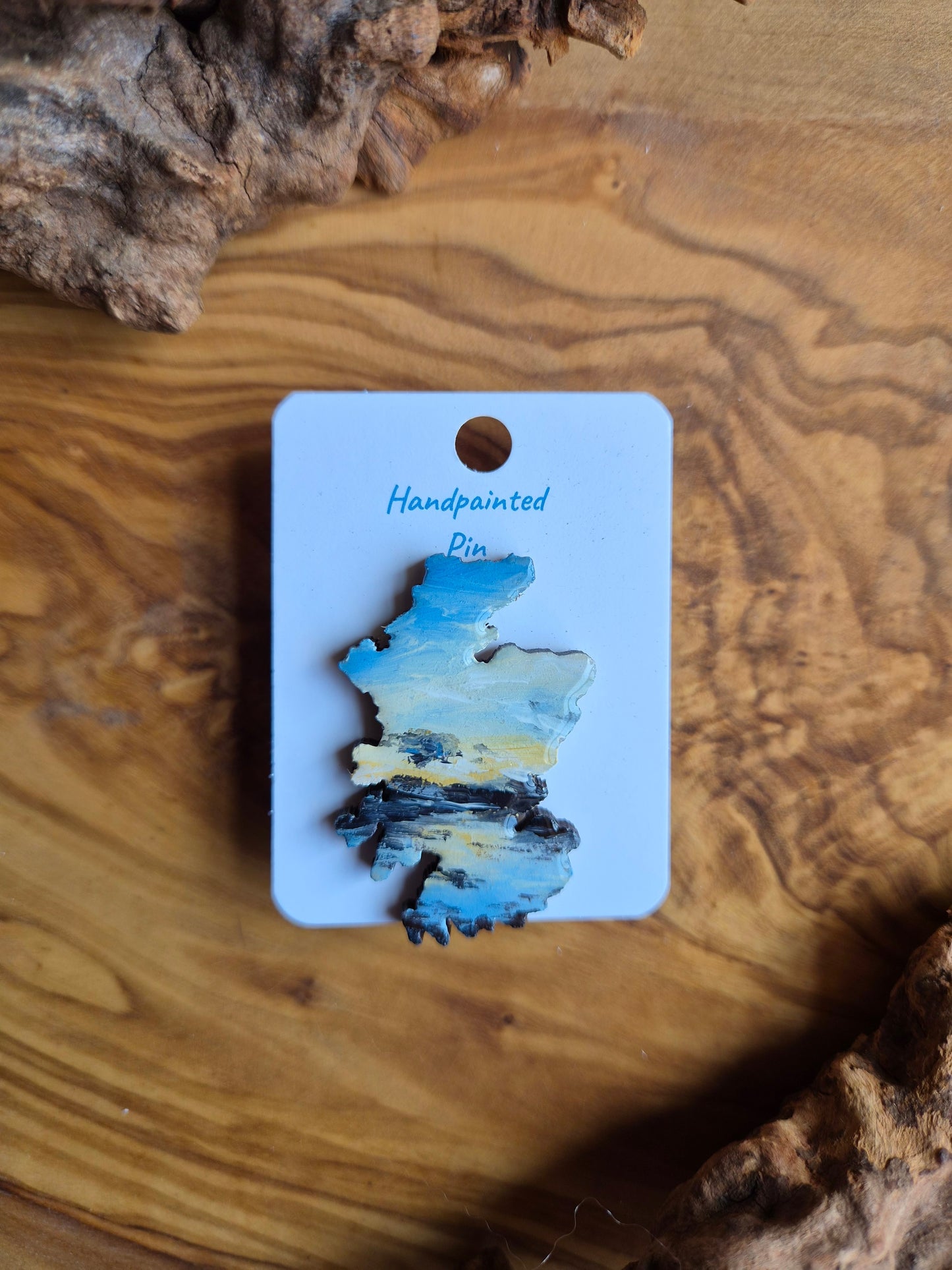 Hand-painted Scotland shaped wooden pin badge with a scottish landscape of findhorn bay at sunset painted on