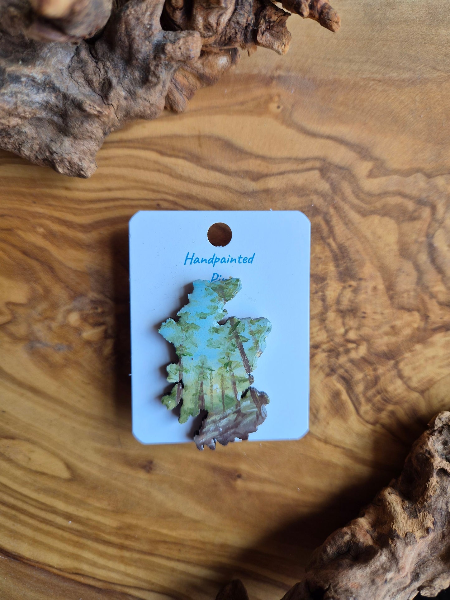 Hand-painted Scotland shaped wooden pin badge with a scottish landscape of cluny forest painted on