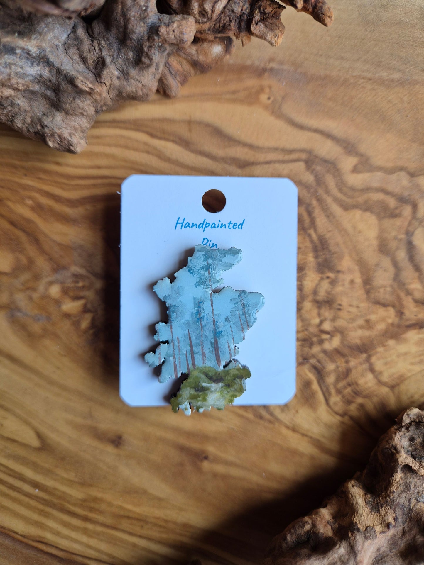 Hand-painted Scotland shaped wooden pin badge with a scottish landscape of roseisle forest painted on