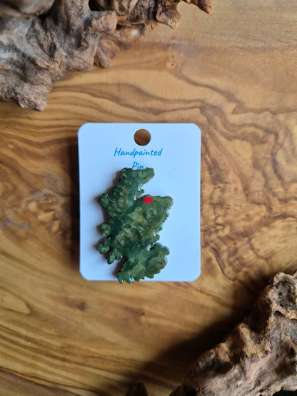 Hand-painted Scotland shaped wooden pin badge with a scottish terrain painted on with a location marker on Forres