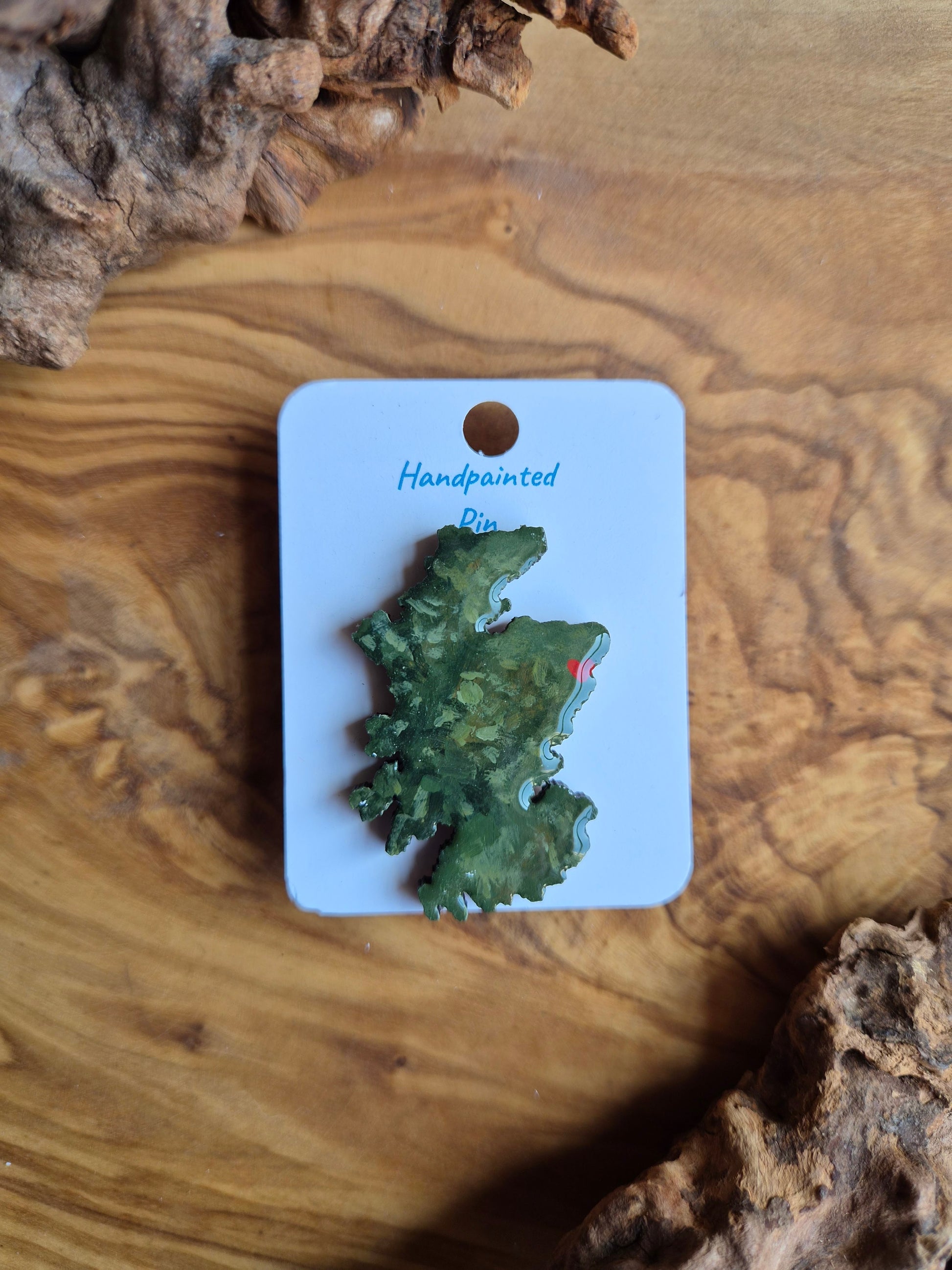 Hand-painted Scotland shaped wooden pin badge with a scottish terrain painted on with a location marker on Aberdeen