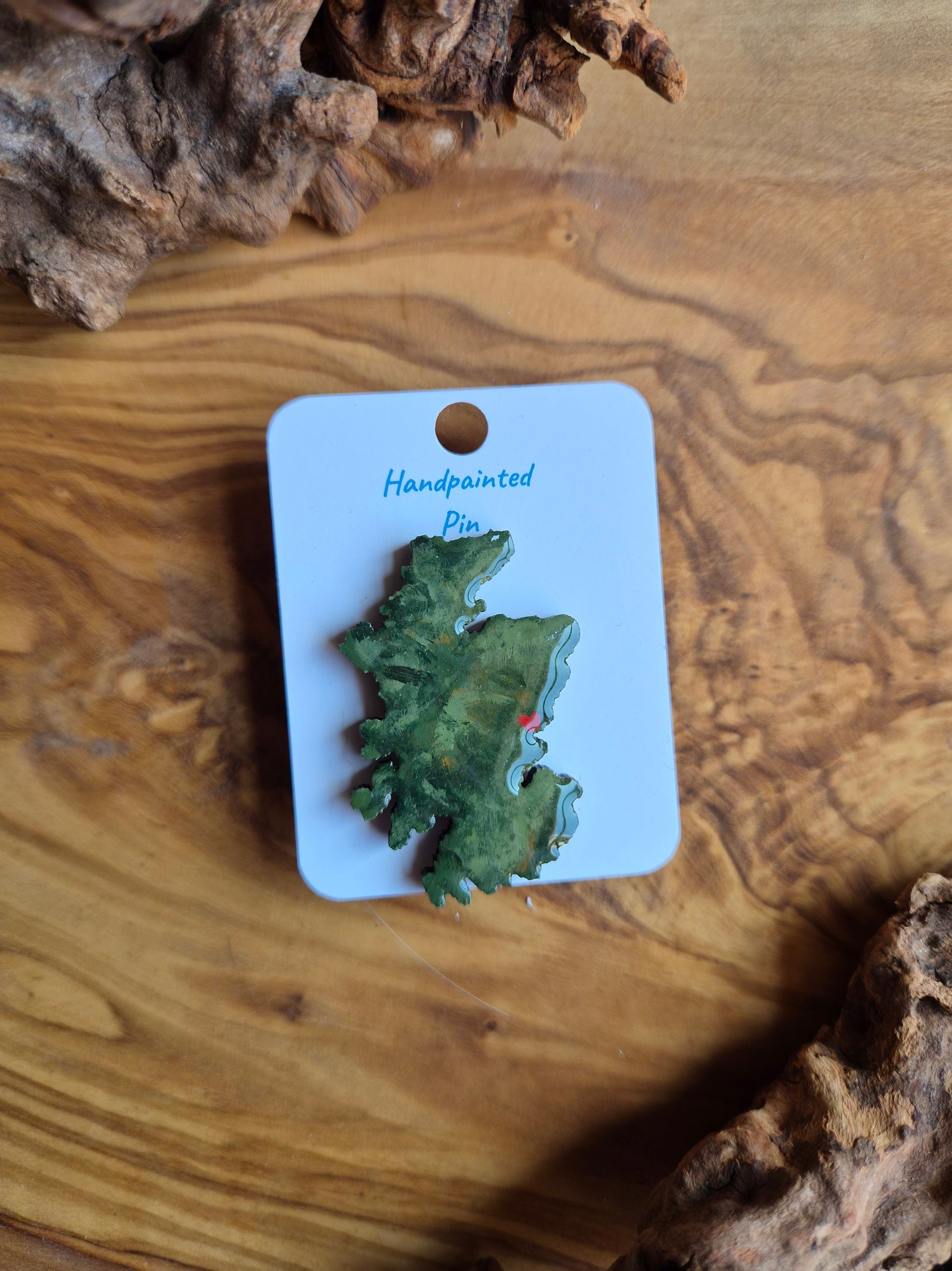 Hand-painted Scotland shaped wooden pin badge with a scottish terrain painted on with a location marker on Dundee