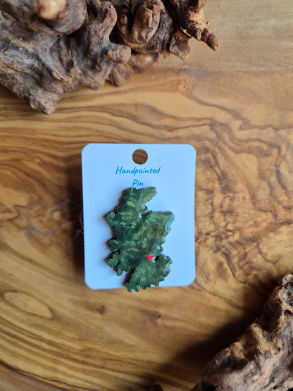 Hand-painted Scotland shaped wooden pin badge with a scottish terrain painted on with a location marker on Falkirk