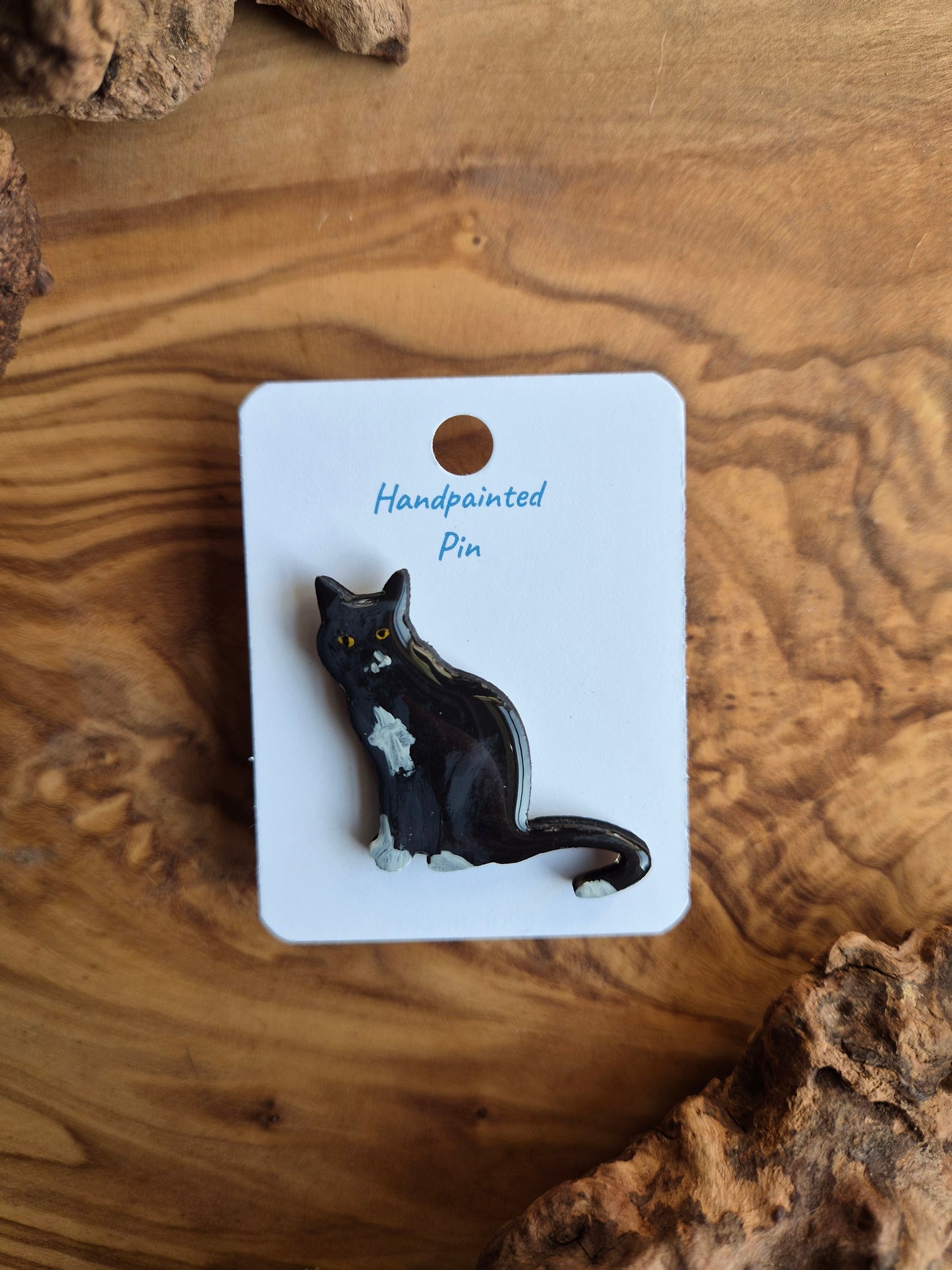 Hand-painted wooden pin badge of a black and white coloured cat