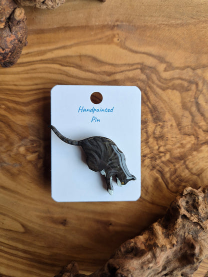 Hand-painted wooden pin badge of a dark tabby coloured cat with white