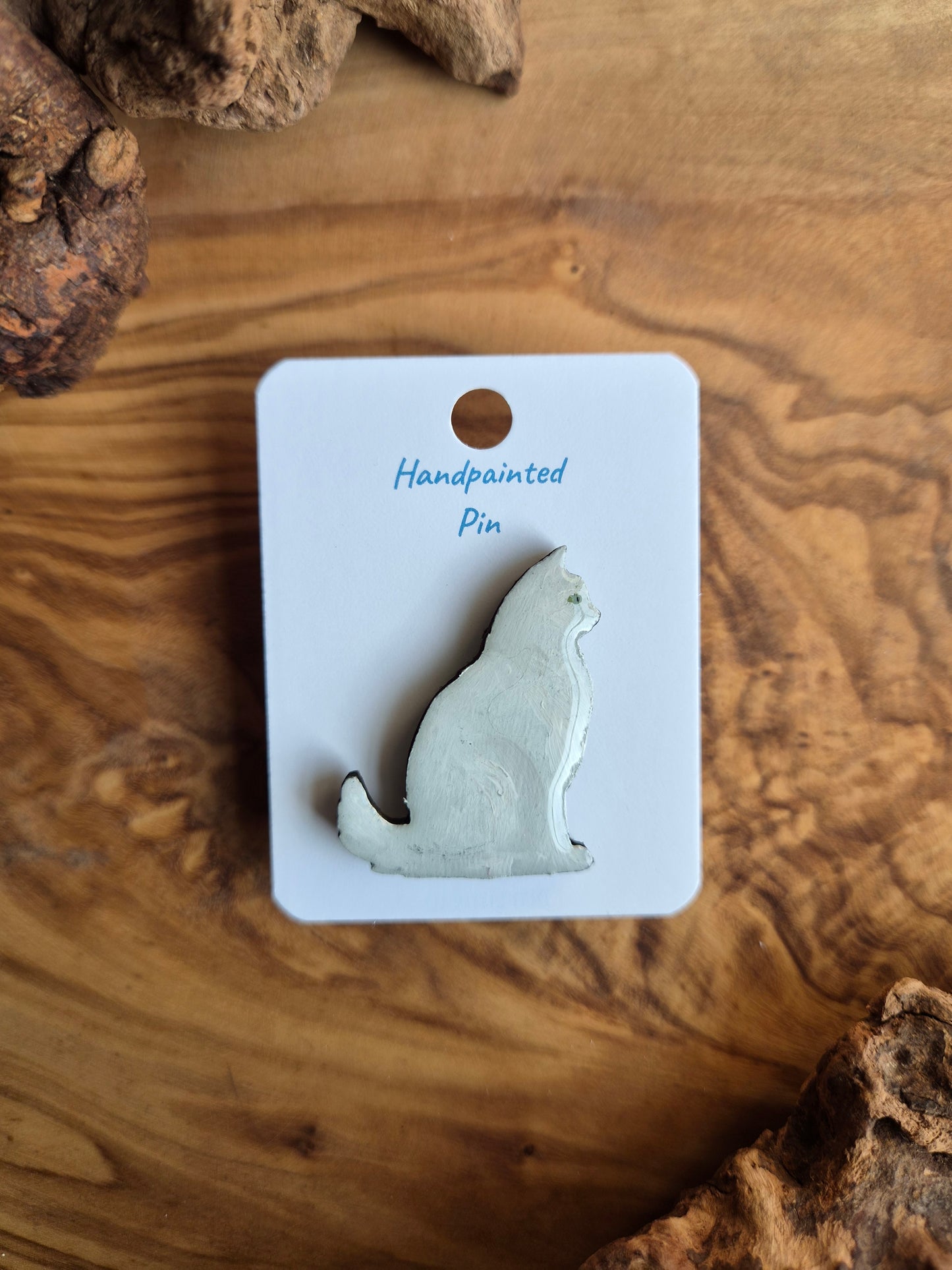 Hand-painted wooden pin badge of a fluffy white with green eyes cat