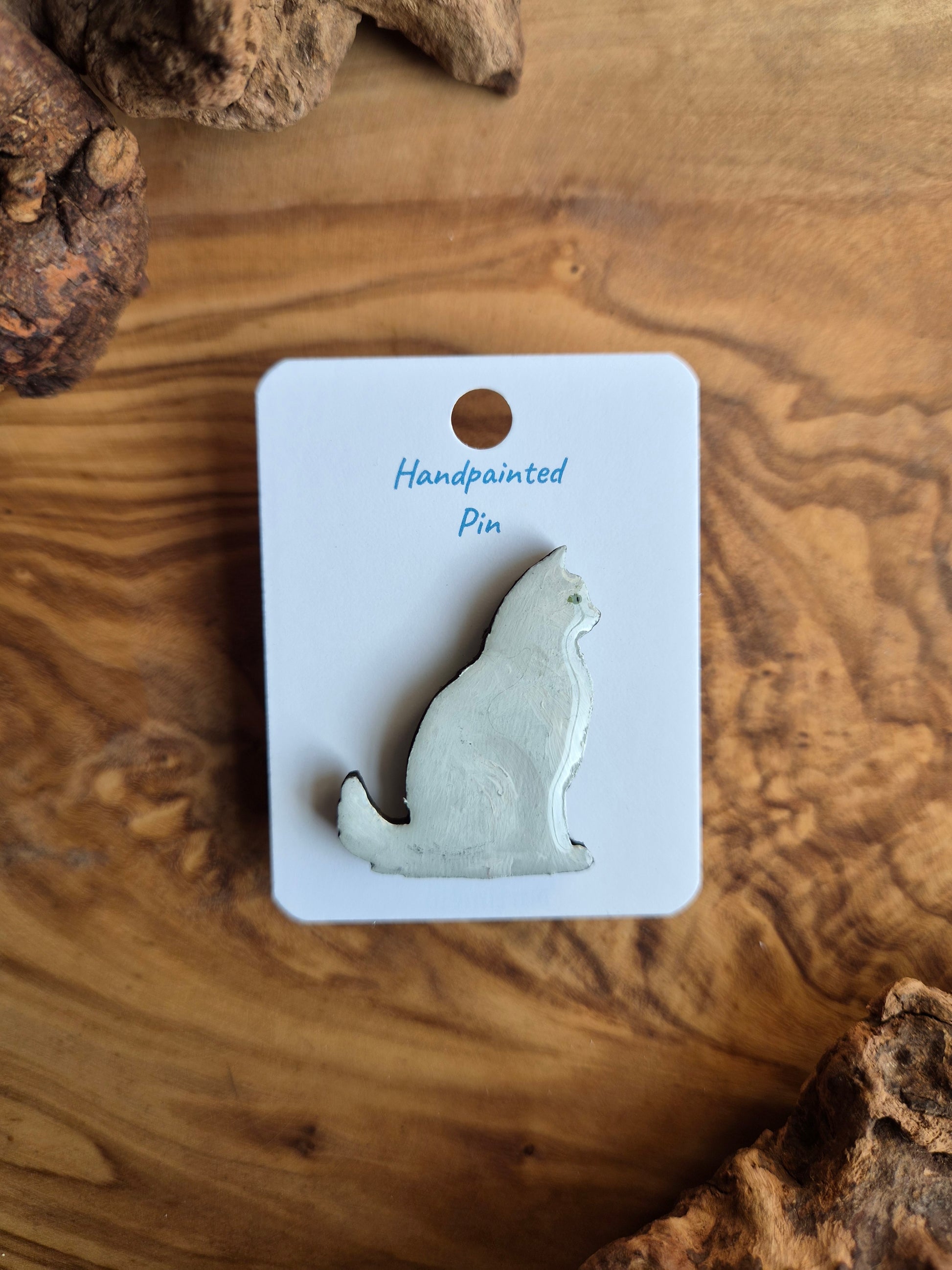 Hand-painted wooden pin badge of a fluffy white with green eyes cat